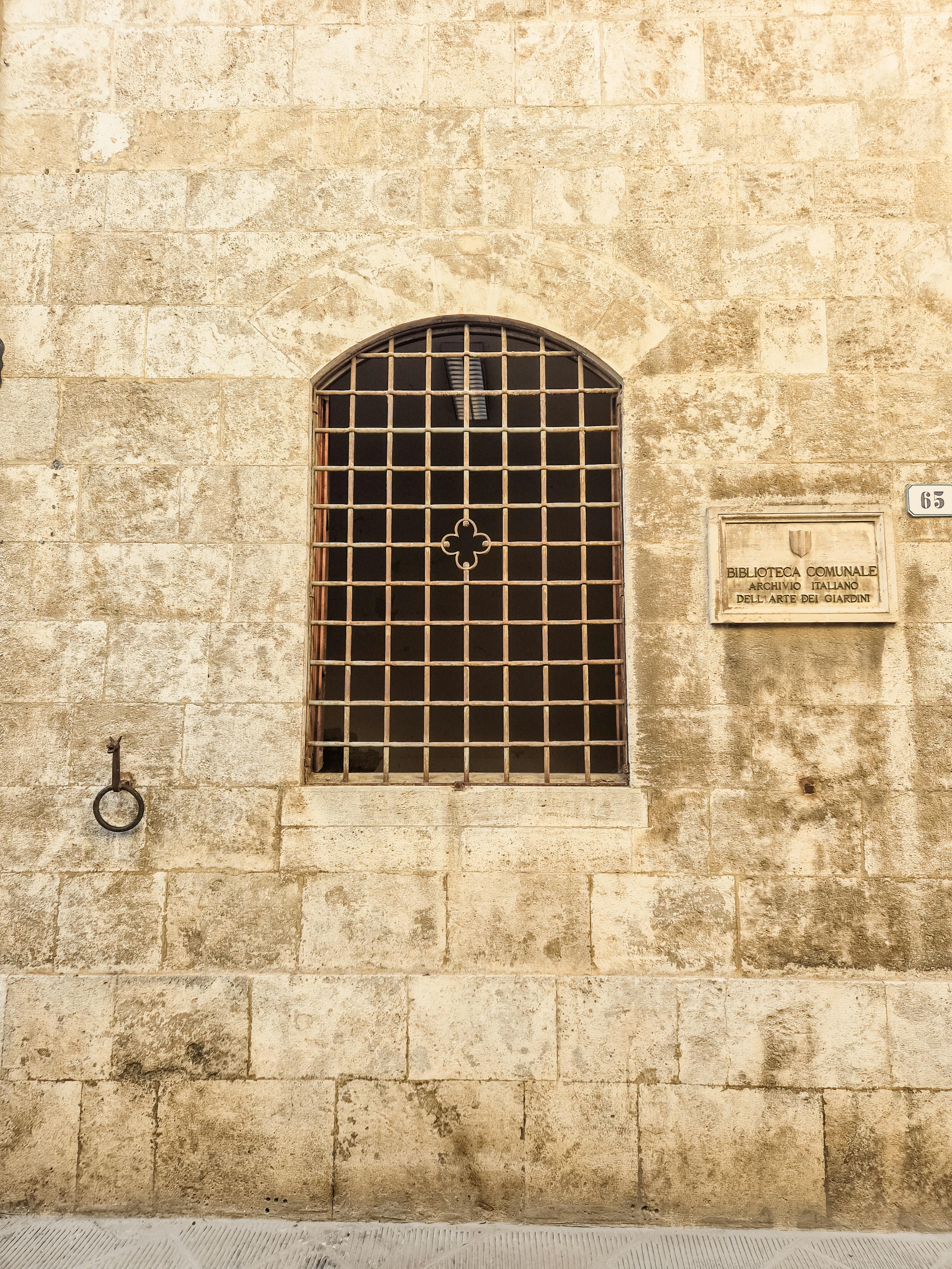 Δωρεάν Vintage πέτρινος τοίχος με τοξωτό παράθυρο με σχέδιο πλέγματος, που θυμίζει ιστορική αρχιτεκτονική. Φωτογραφία από στοκ φωτογραφιών