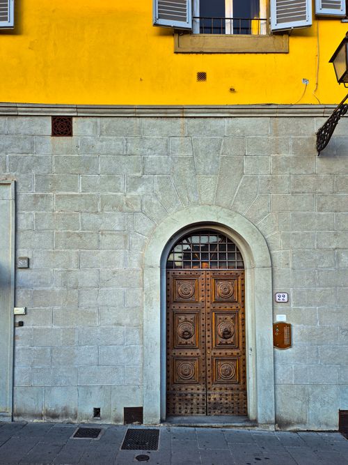 Free Elegant stone facade in Mediterranean style featuring an ornate wooden door under a bright yellow wall. Stock Photo
