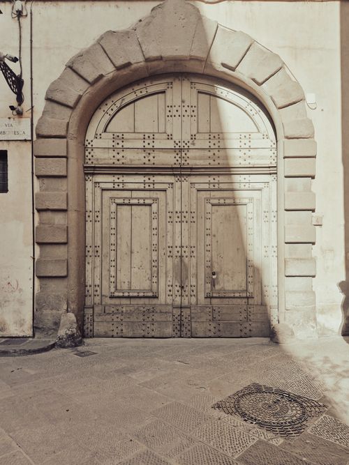 Free A vintage wooden door set within an impressive stone arch, exuding historical charm and architectural elegance. Stock Photo