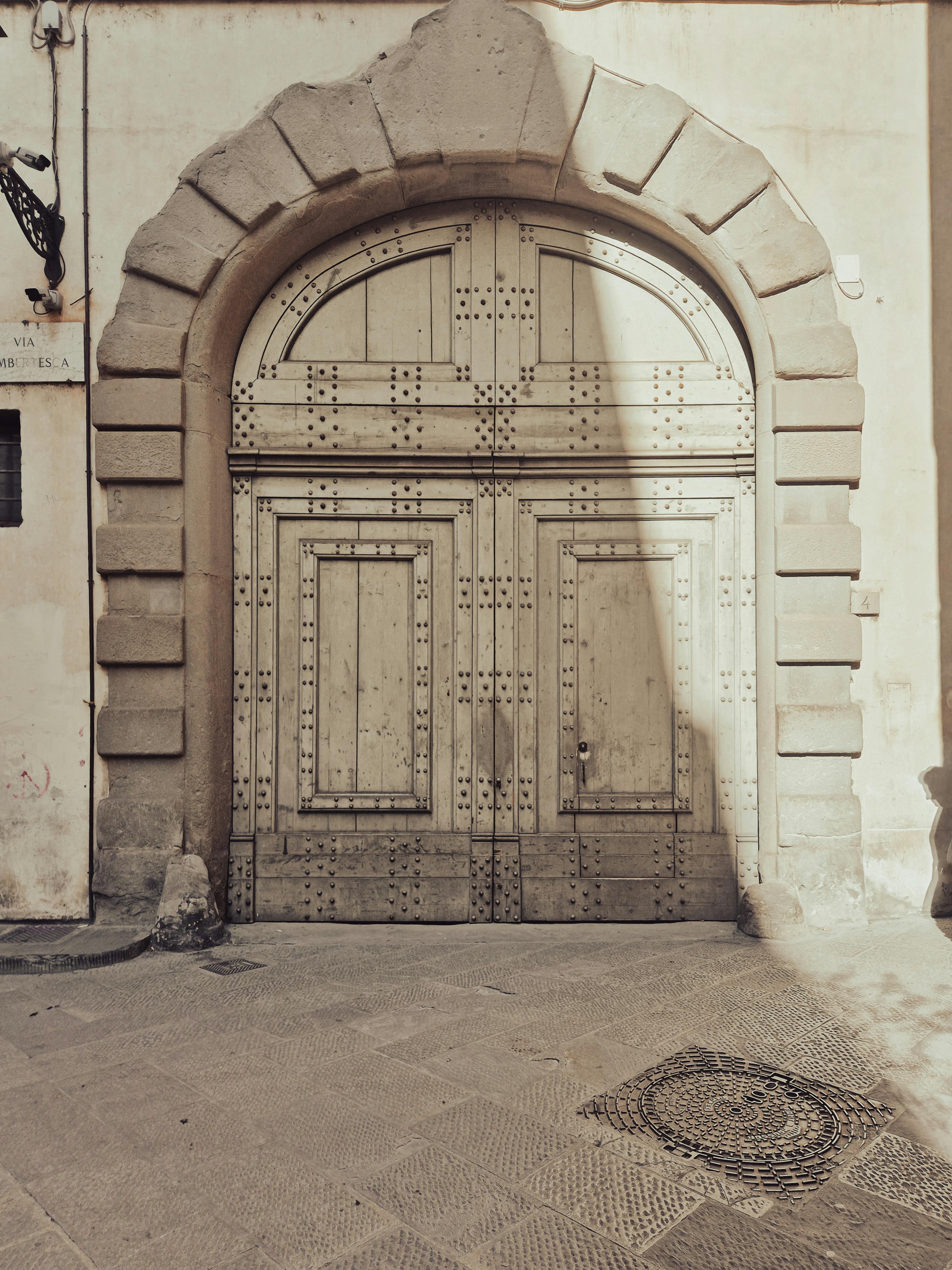 Δωρεάν Μια vintage ξύλινη πόρτα τοποθετημένη μέσα σε μια εντυπωσιακή πέτρινη καμάρα, που αποπνέει ιστορική γοητεία και αρχιτεκτονική κομψότητα. Φωτογραφία από στοκ φωτογραφιών