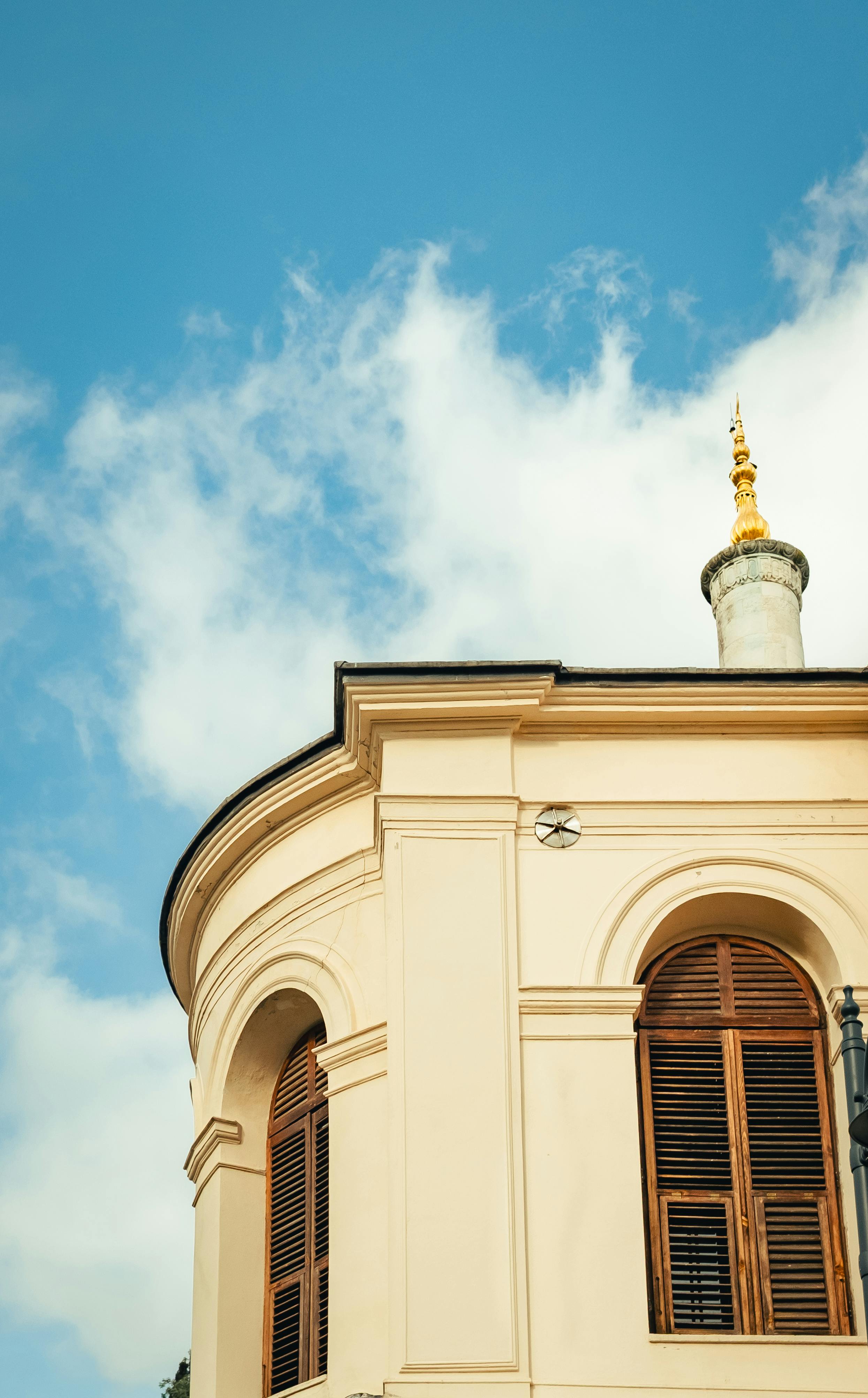 Gratis Elegant kremfarget bygning med spir under en klar blå himmel, som fanger klassisk arkitektonisk skjønnhet. Arkivbilde