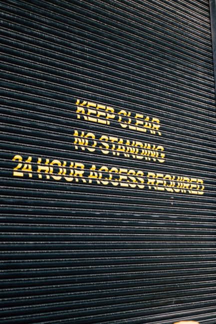 Close-up of a corrugated metal roller door with safety signage in yellow.