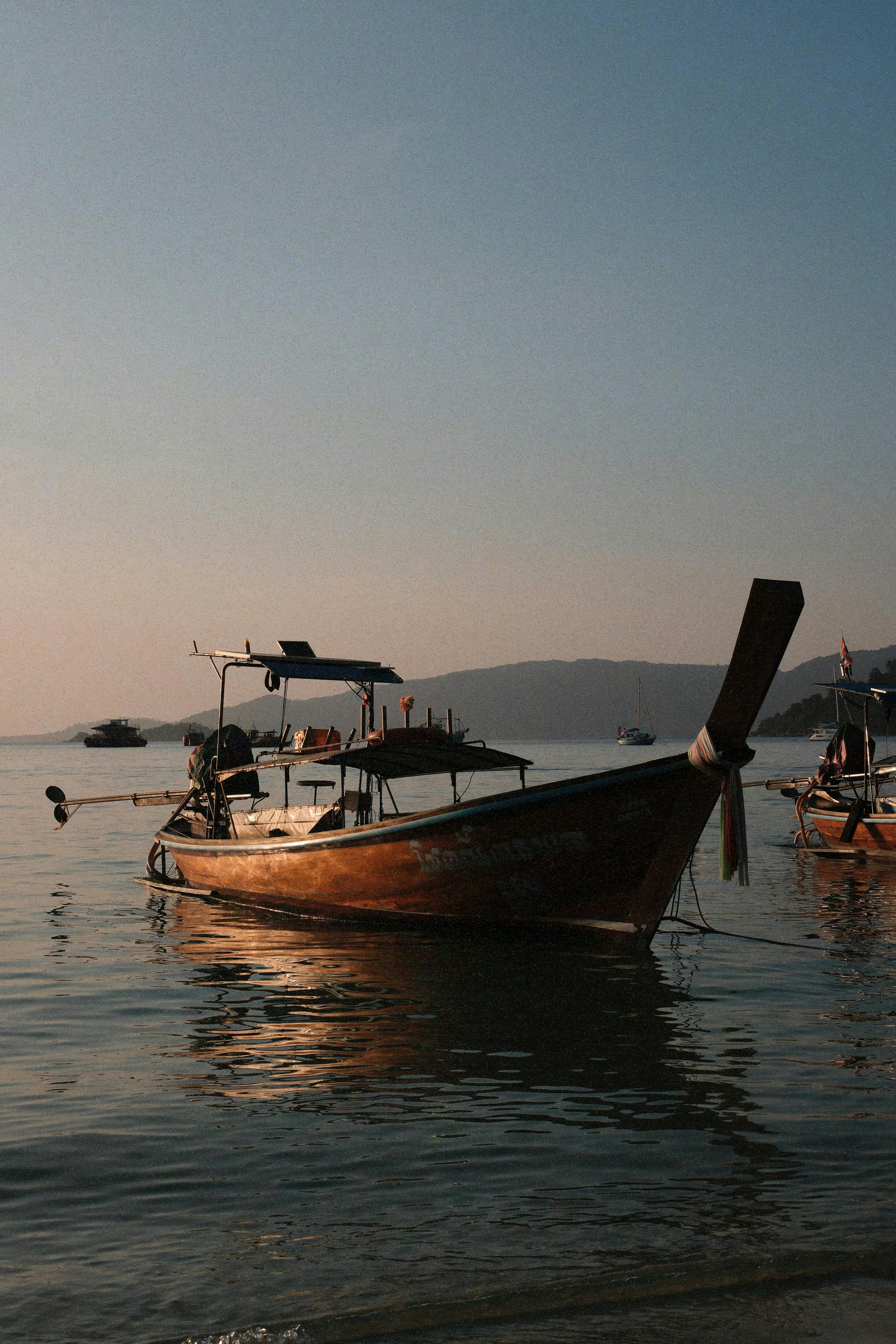 Kostenlos Ein traditionelles Langboot gleitet sanft auf ruhigen Gewässern im Sonnenuntergang und weckt Assoziationen von Gelassenheit und Abenteuerlust. Stock-Foto