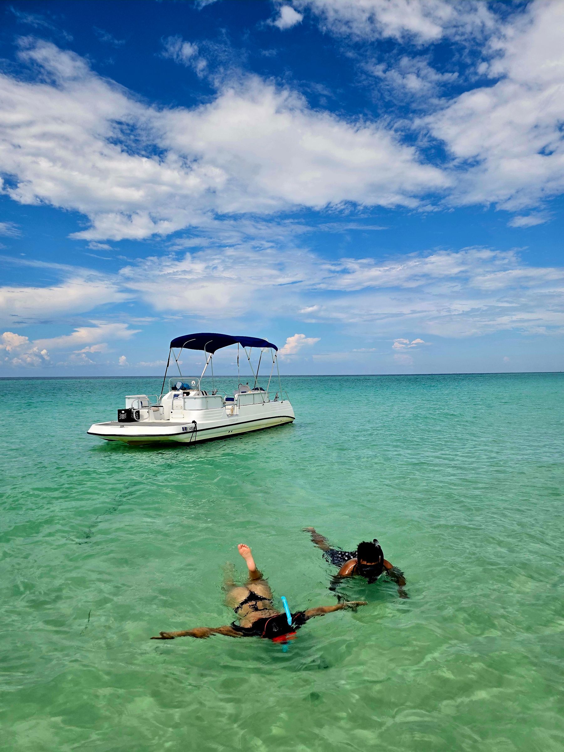 People snorkeling in clear coastal water near a boat