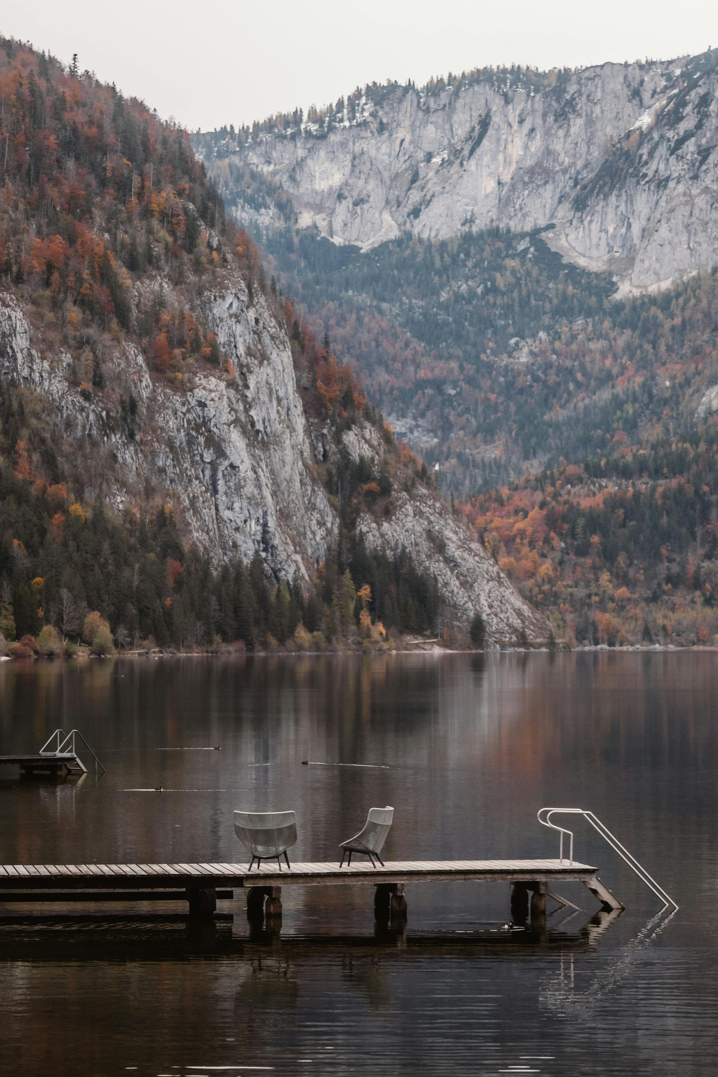 Kostenlos Entdecken Sie Ruhe und Erholung an diesem malerischen Bergsee mit Steg inmitten herbstlicher Farben. Stock-Foto
