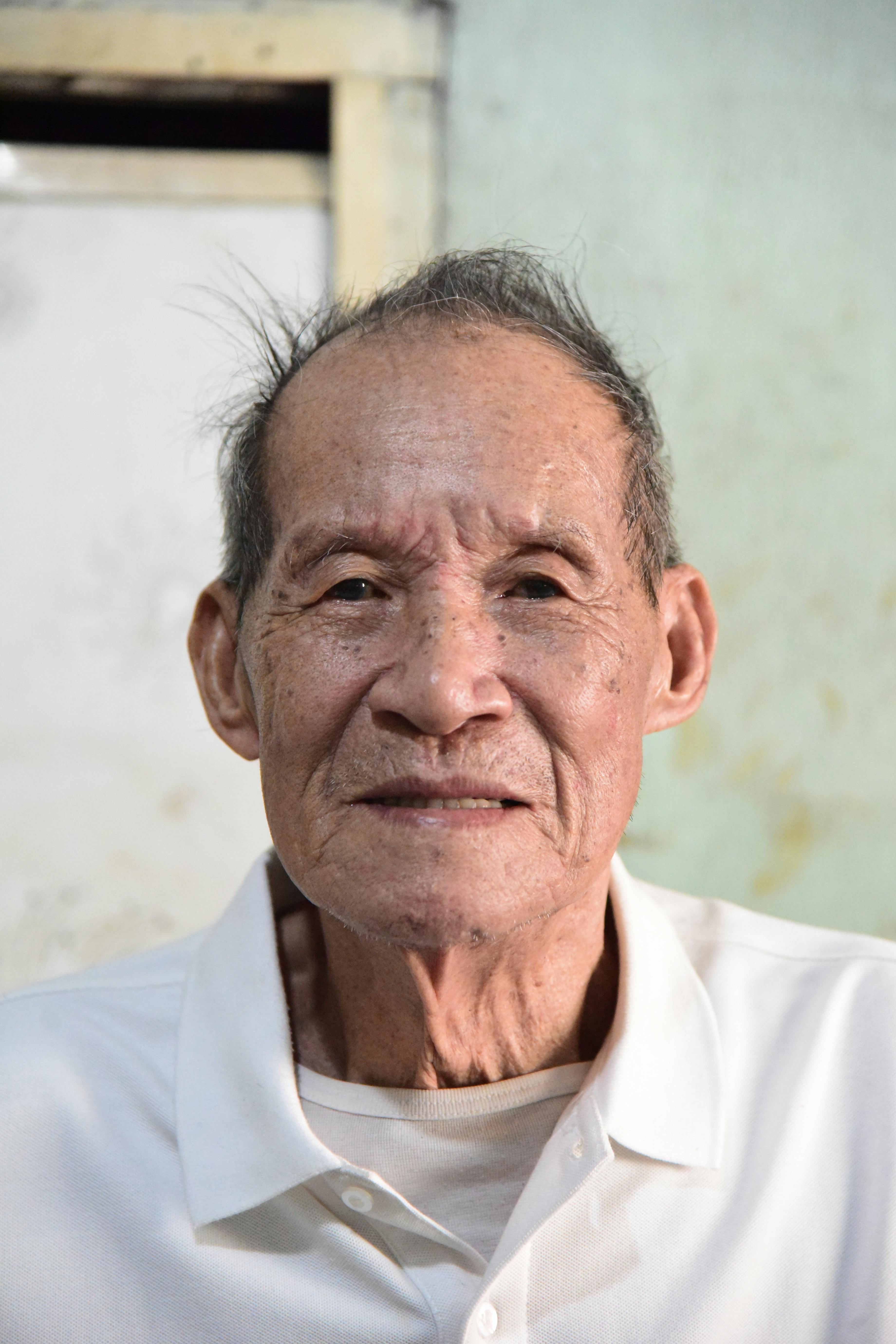 Kostenlos Nahaufnahme eines lächelnden älteren Mannes in einem weißen Hemd in einem Innenraum. Stock-Foto