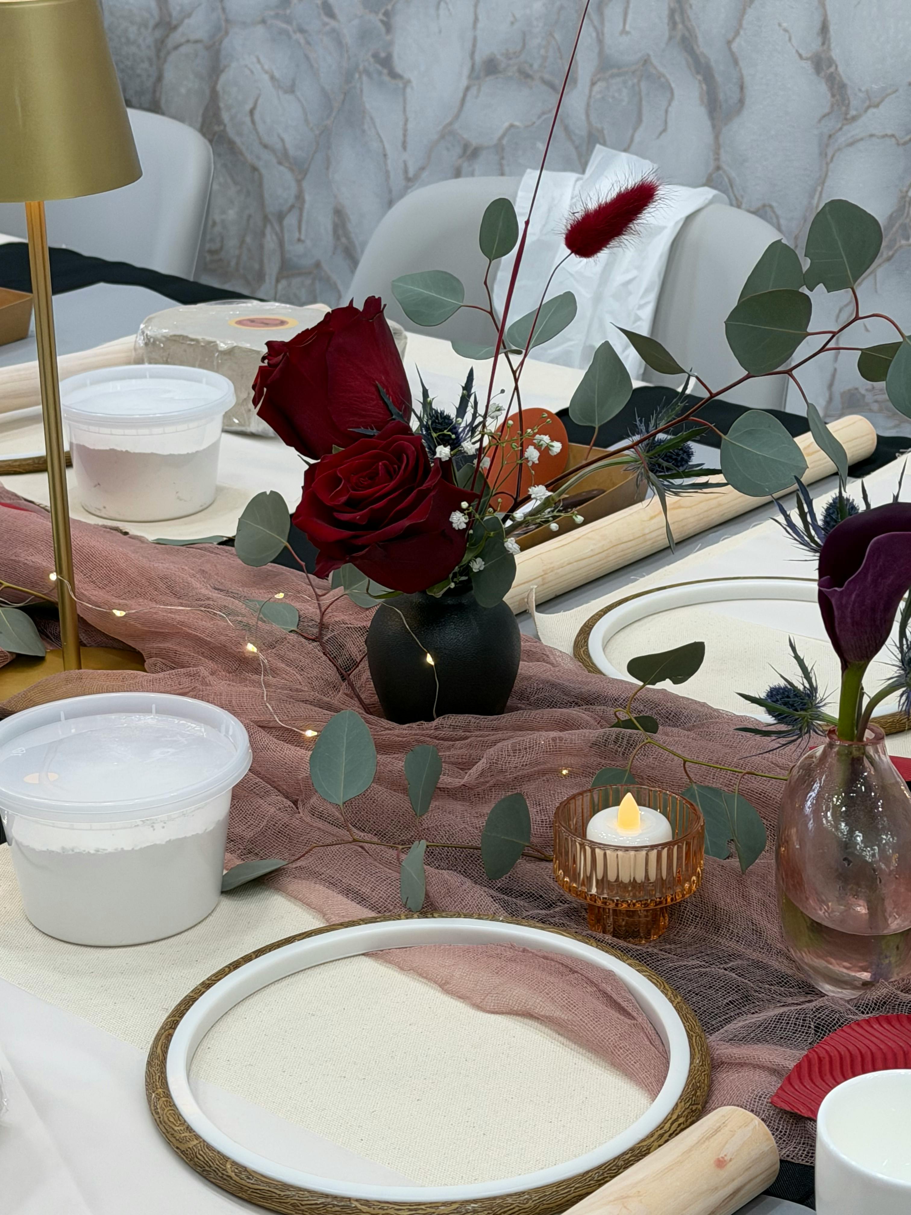 Kostenlos Eine stilvolle Tischdekoration mit roten Rosen, Eukalyptus und elegantem Dekor in sanfter Atmosphäre. Stock-Foto