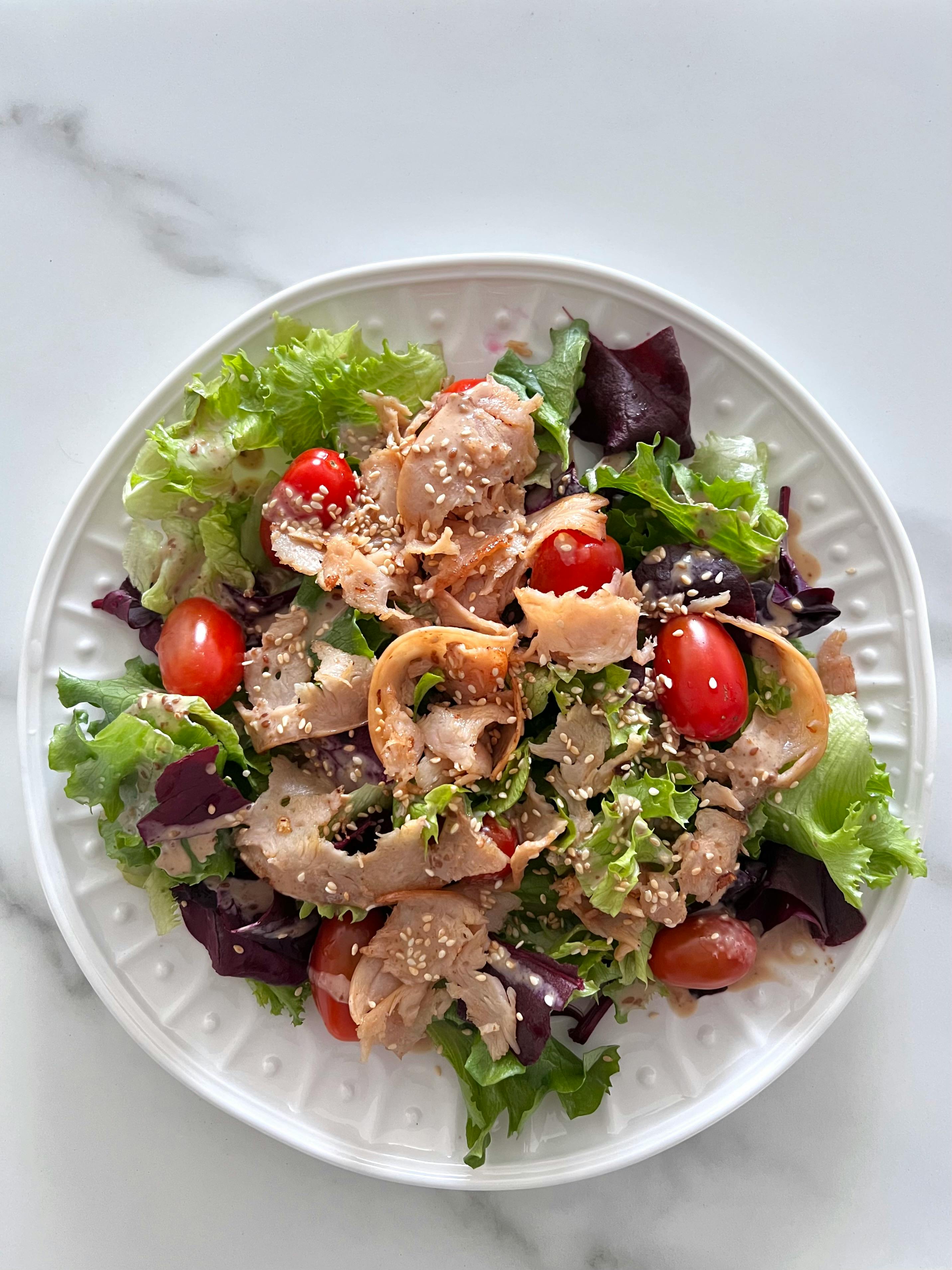 Kostenlos Köstlicher Hühnersalat mit Kirschtomaten und gemischtem Salat auf einem weißen Teller. Stock-Foto