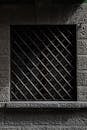 Shadowed Window with Iron Grate on Stone Wall