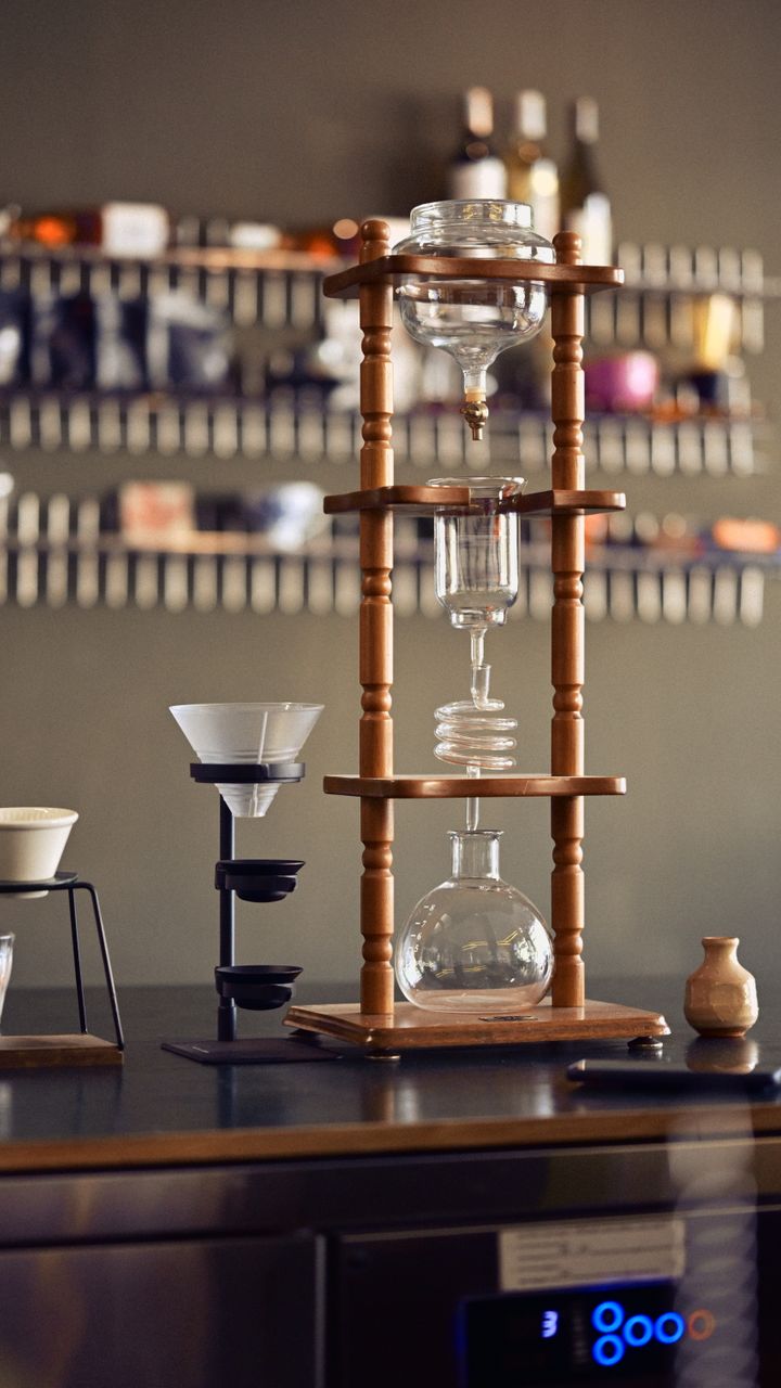 Hanging copper pot rack holding stainless steel kettles above a coffee and tea bar