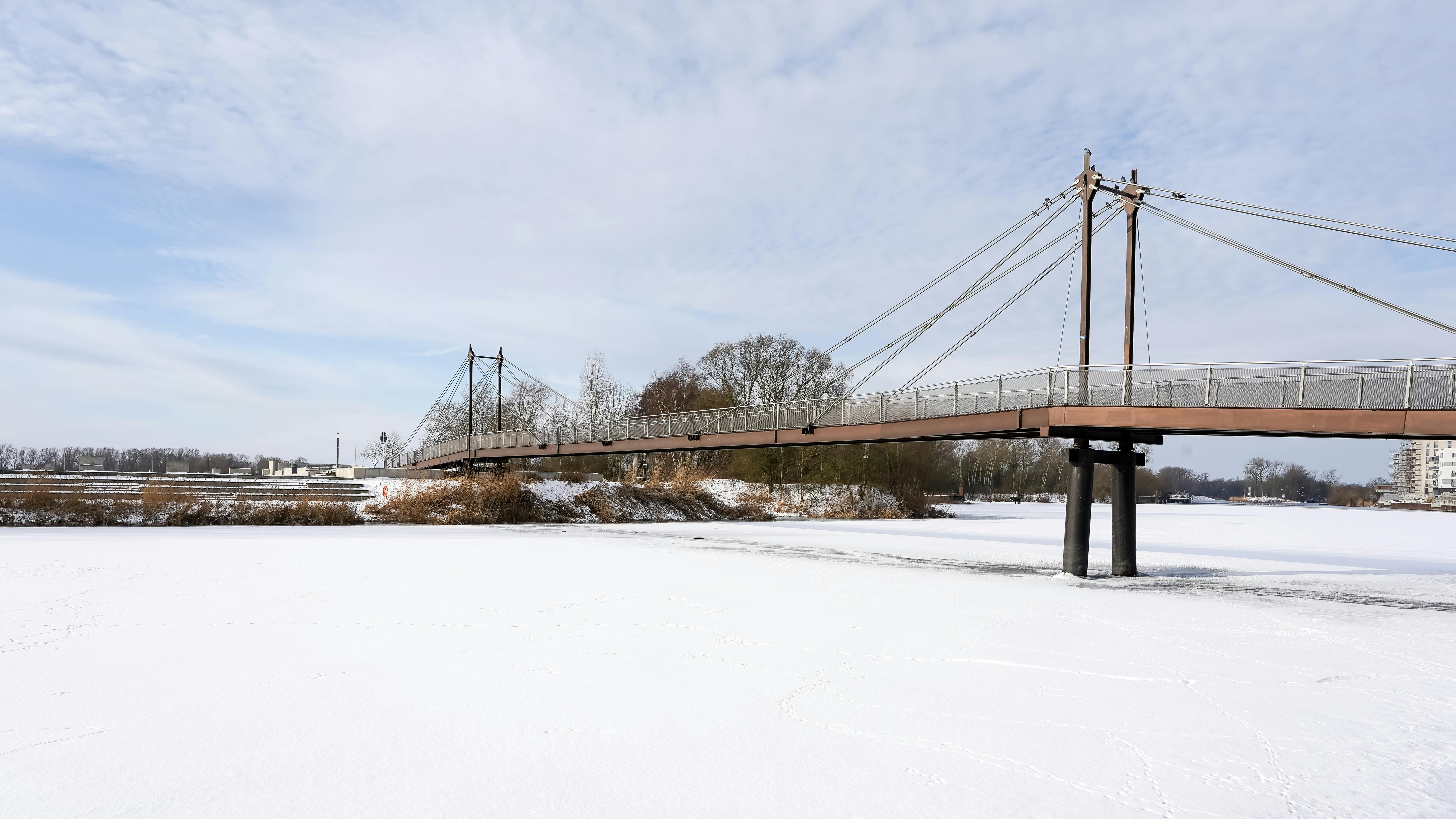Kostenlos Malerische Ansicht einer Hängebrücke über einen zugefrorenen Kanal in Geesthacht, Deutschland, im Winter. Stock-Foto