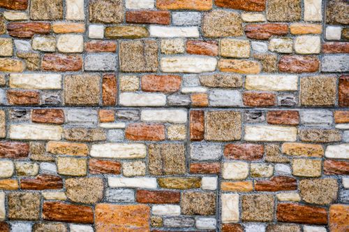 Free Close-up of a textured brick wall with diverse colors and patterns. Stock Photo