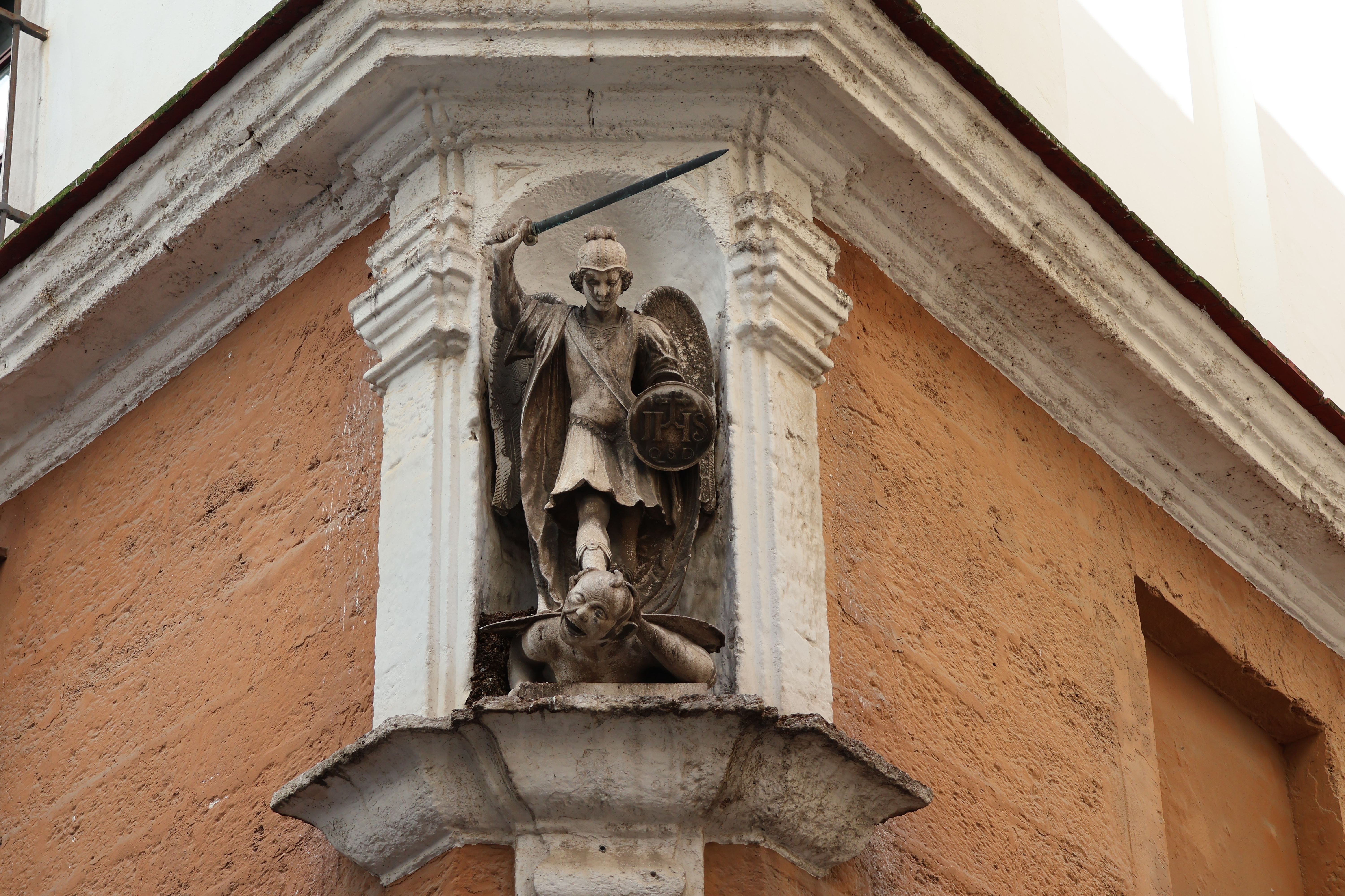 Detailed view of St. Michael the Archangel statue on a historic Cádiz building corner.