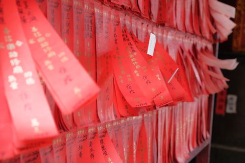 Free Close-up of red wish charms with inscriptions hanging inside a cultural site. Stock Photo