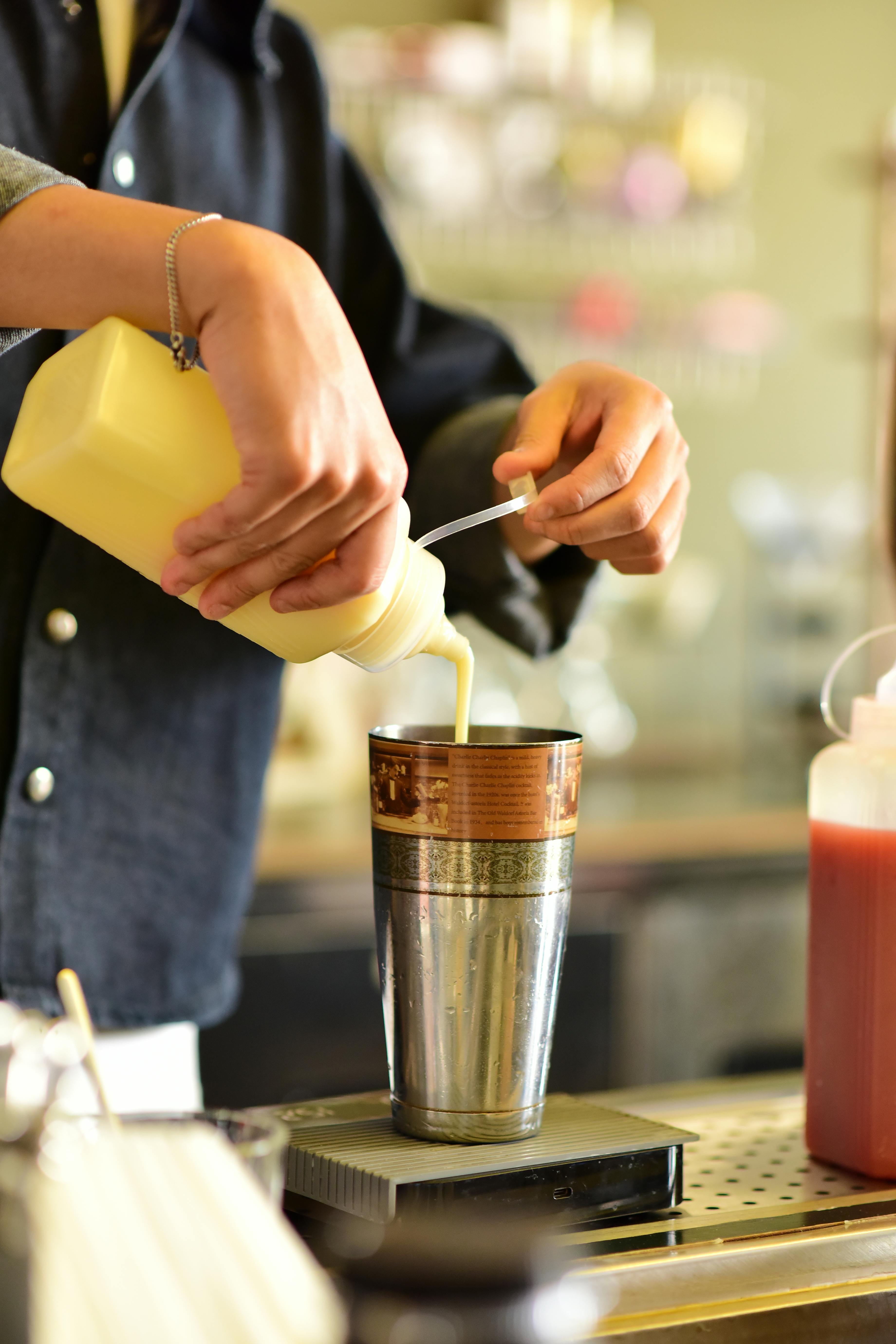 Kostenlos Ein Barkeeper bereitet gekonnt und präzise einen Cocktail in einem eleganten Metallshaker zu. Stock-Foto