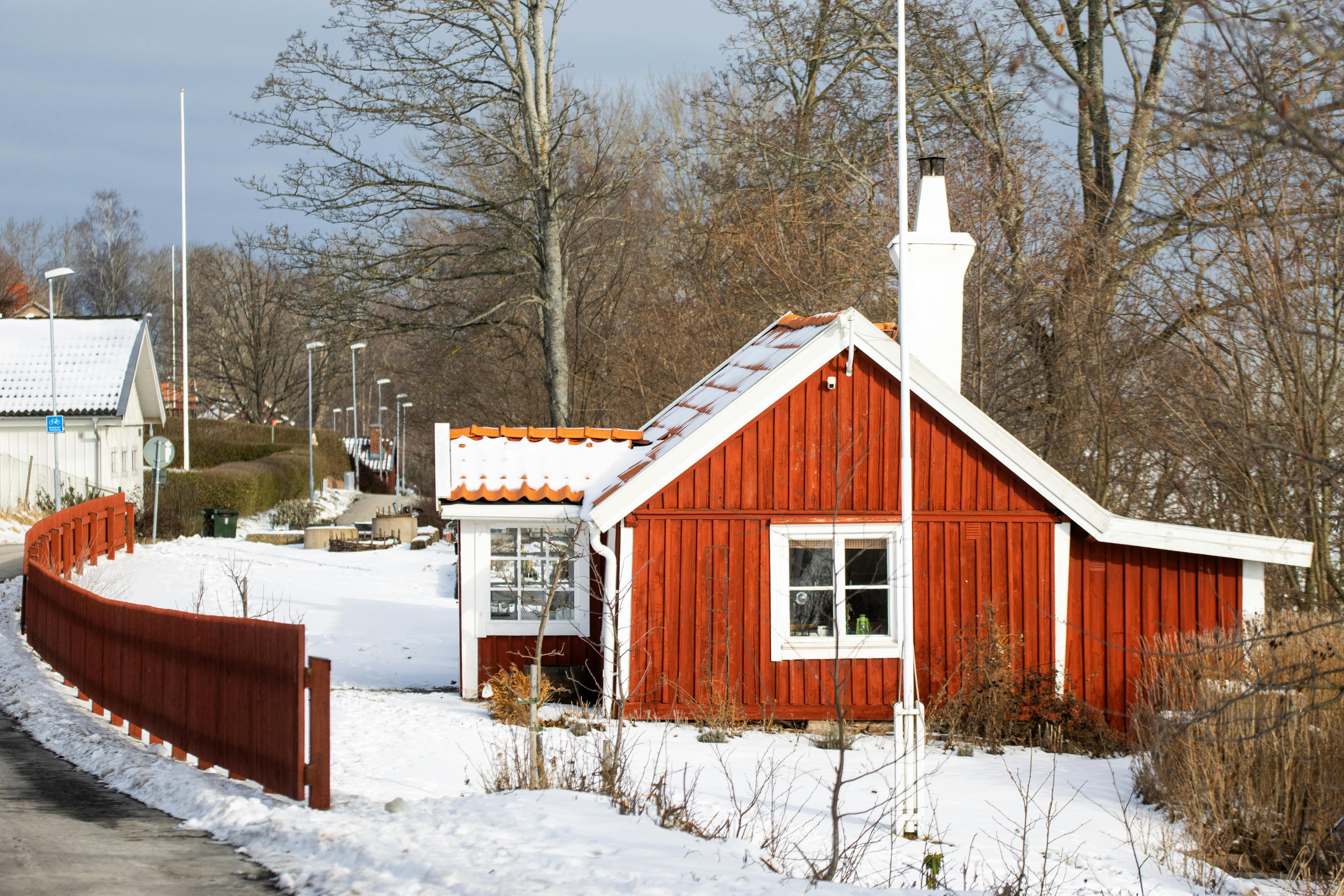 Δωρεάν Ένα γραφικό κόκκινο εξοχικό σπίτι σε ένα χιονισμένο περιβάλλον στο Γιένσεπινγκ, που αποτυπώνει τη σουηδική χειμερινή γοητεία. Φωτογραφία από στοκ φωτογραφιών