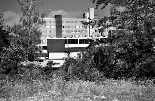 Black and white photo of a modern building surrounded by trees and grass.
