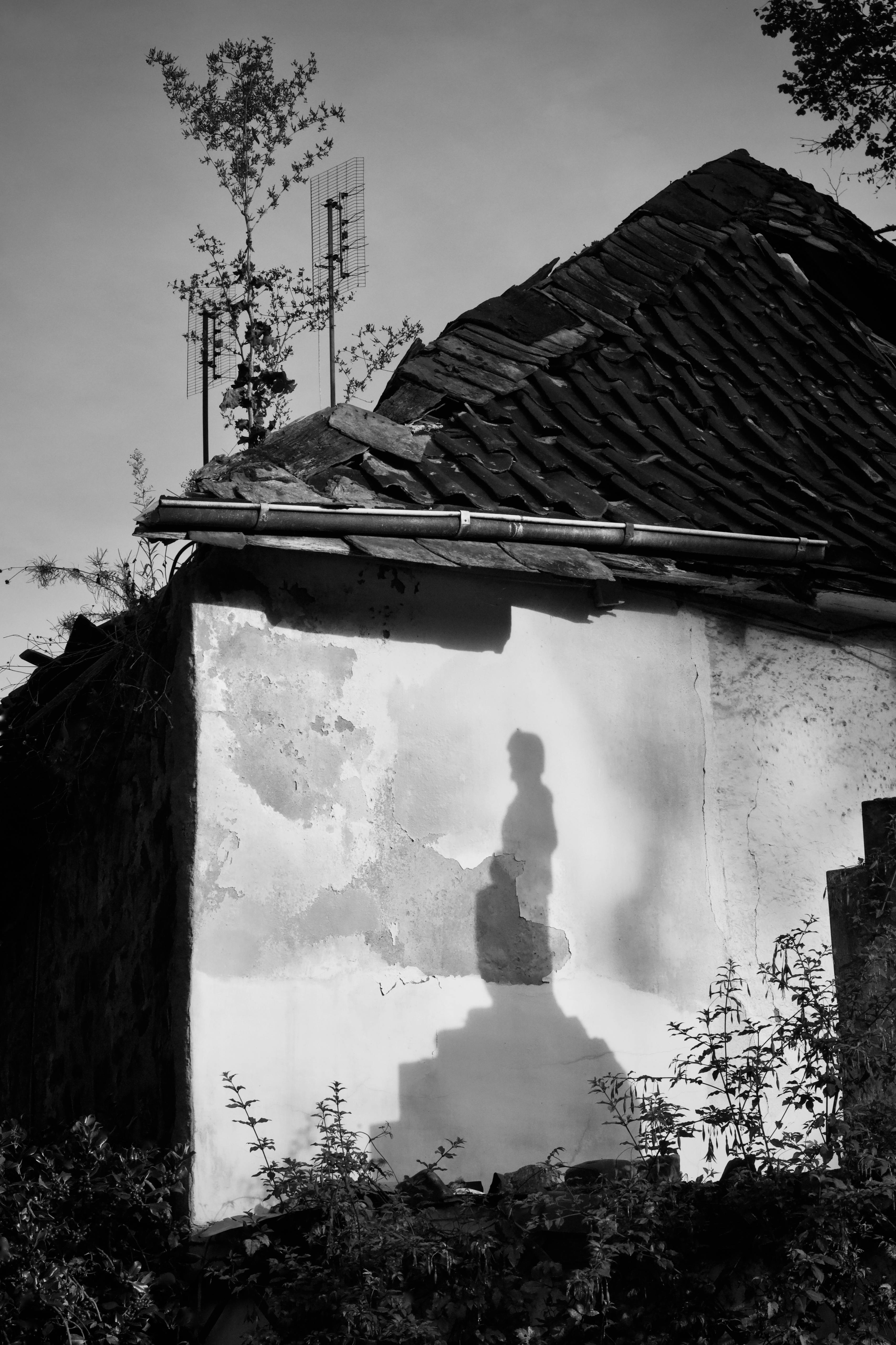 Δωρεάν Ασπρόμαυρη φωτογραφία που αποτυπώνει μια σιλουέτα στο εξωτερικό ενός ρουστίκ κτιρίου. Φωτογραφία από στοκ φωτογραφιών