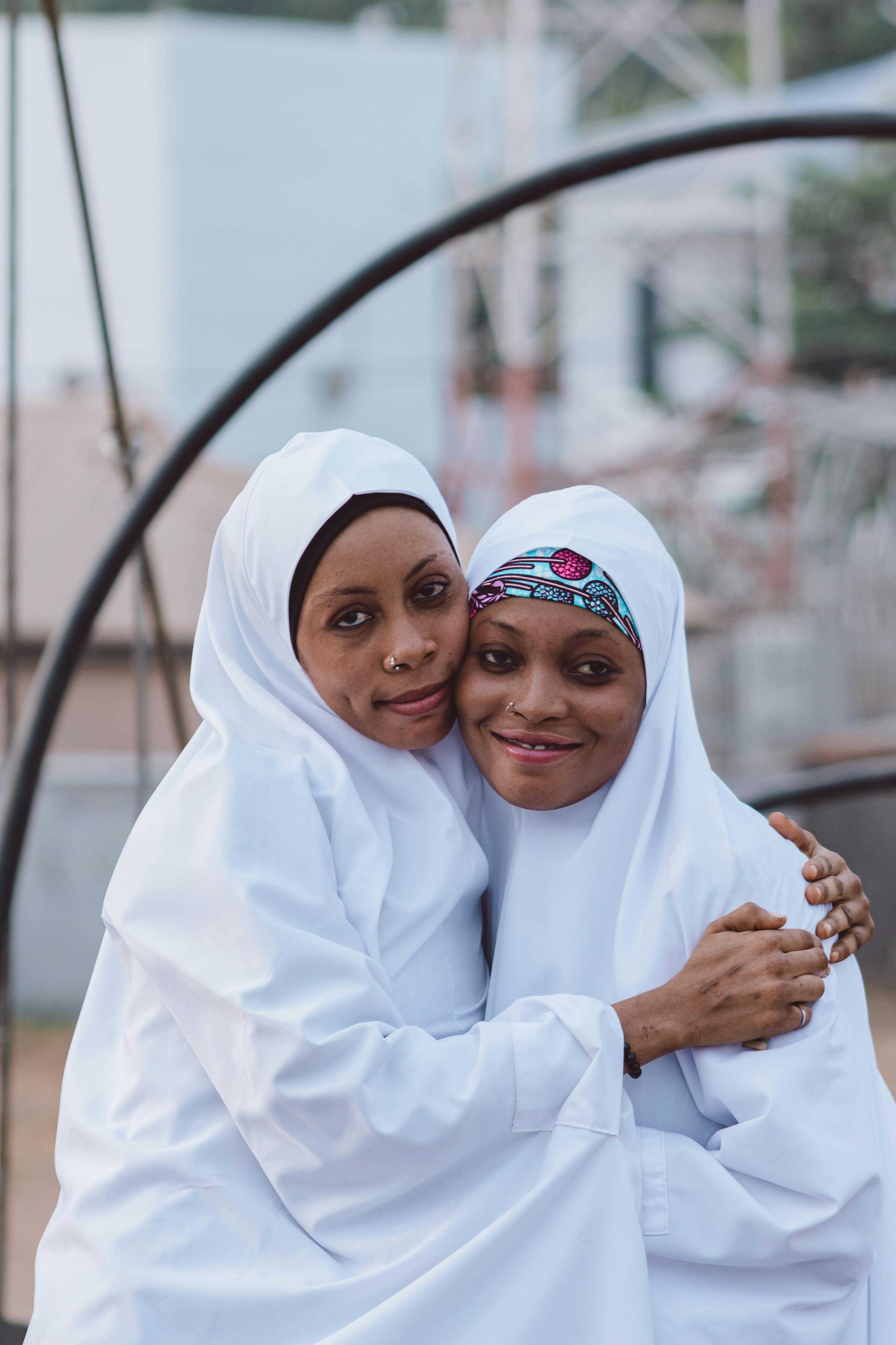 Kostenlos Zwei Frauen in traditioneller Kleidung umarmen sich im Freien und symbolisieren kulturelle Vielfalt und Freundschaft. Stock-Foto