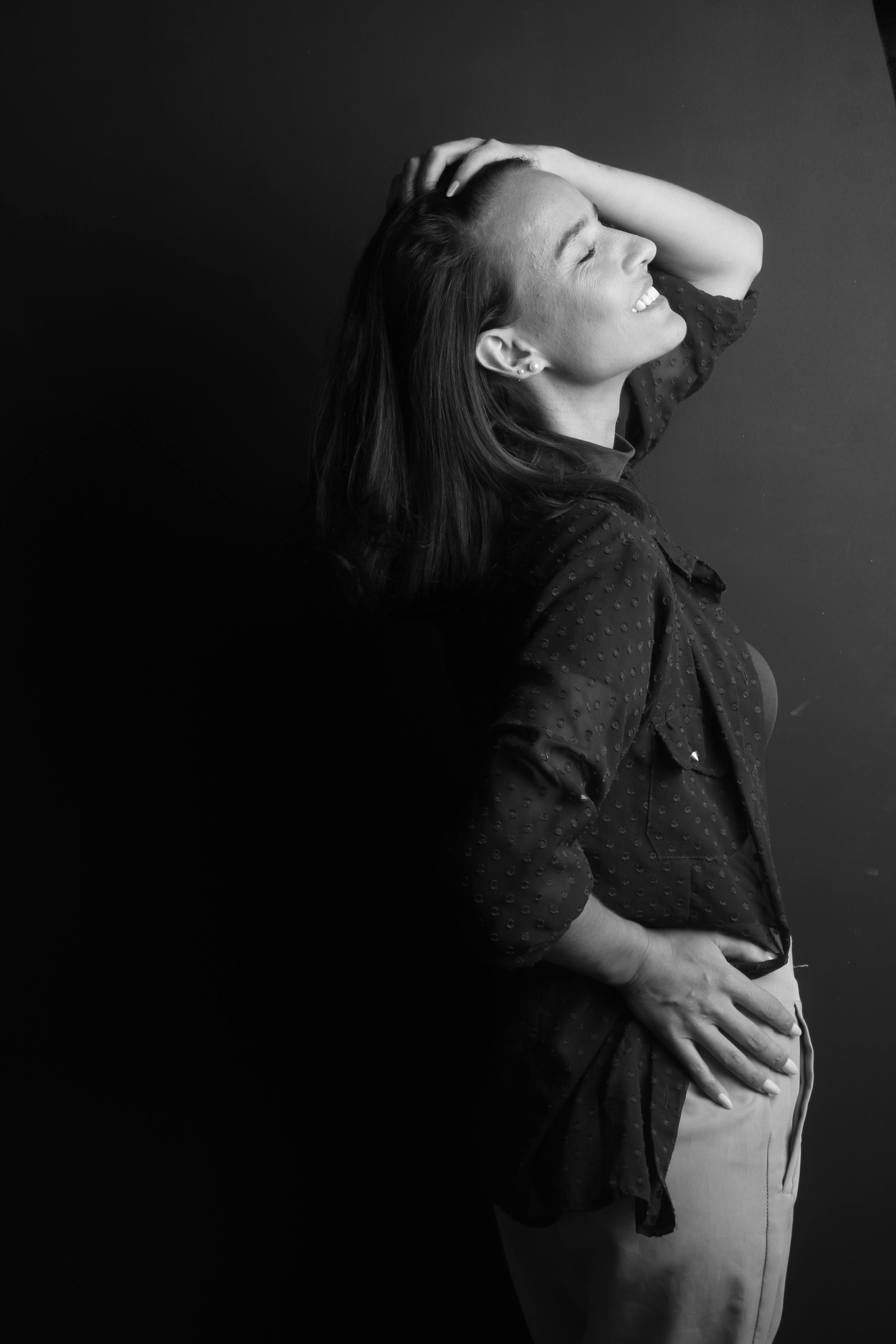 Kostenlos Schwarz-Weiß-Porträt einer lächelnden Frau mit der Hand im Haar, Seitenansicht. Stock-Foto