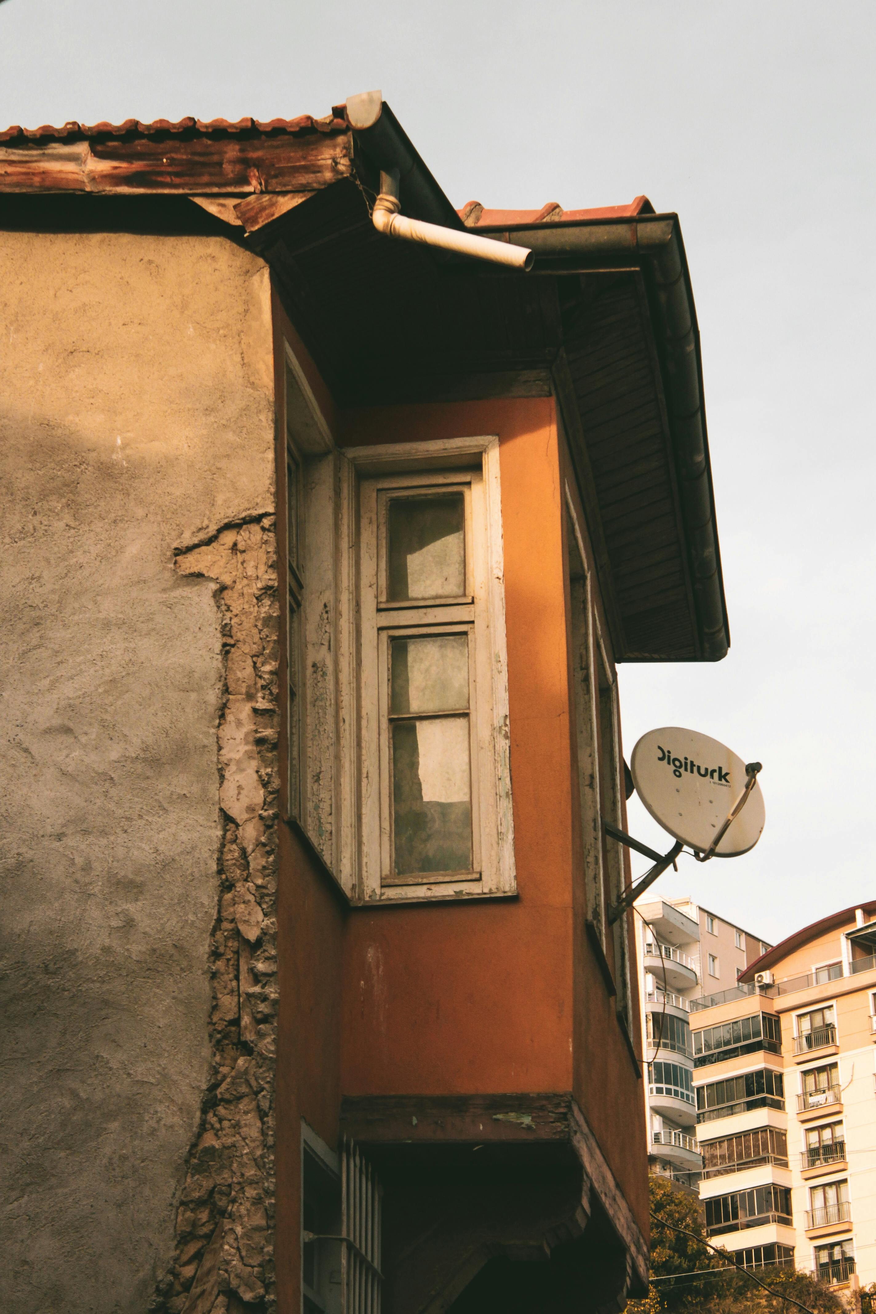 Δωρεάν Παλιό αστικό κτίριο με δορυφορική κεραία κάτω από το ζεστό φως του ηλιοβασιλέματος, που αναδεικνύει τις φθαρμένες υφές. Φωτογραφία από στοκ φωτογραφιών