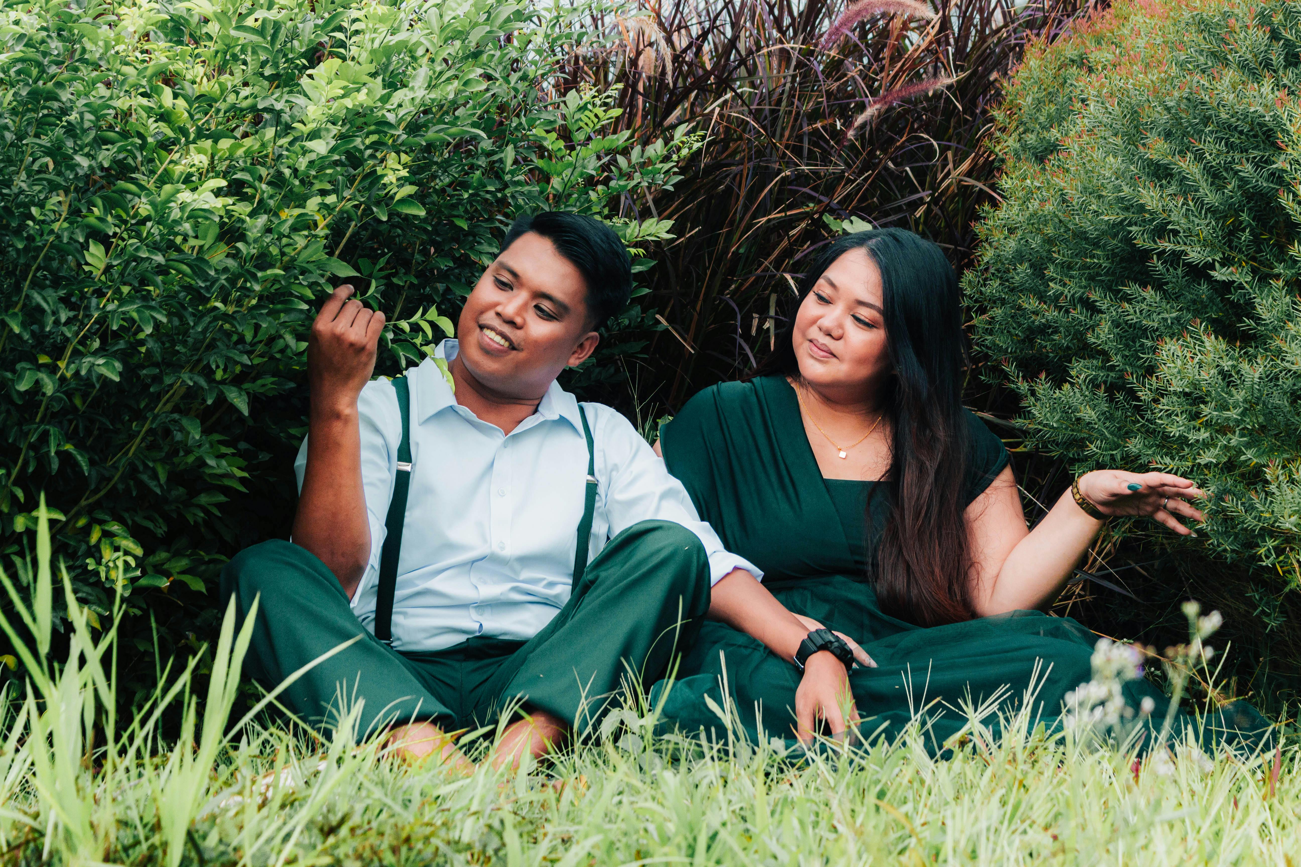 Kostenlos Ein verliebtes Paar sitzt inmitten üppigen Grüns und genießt die Gesellschaft des anderen und die Natur. Stock-Foto