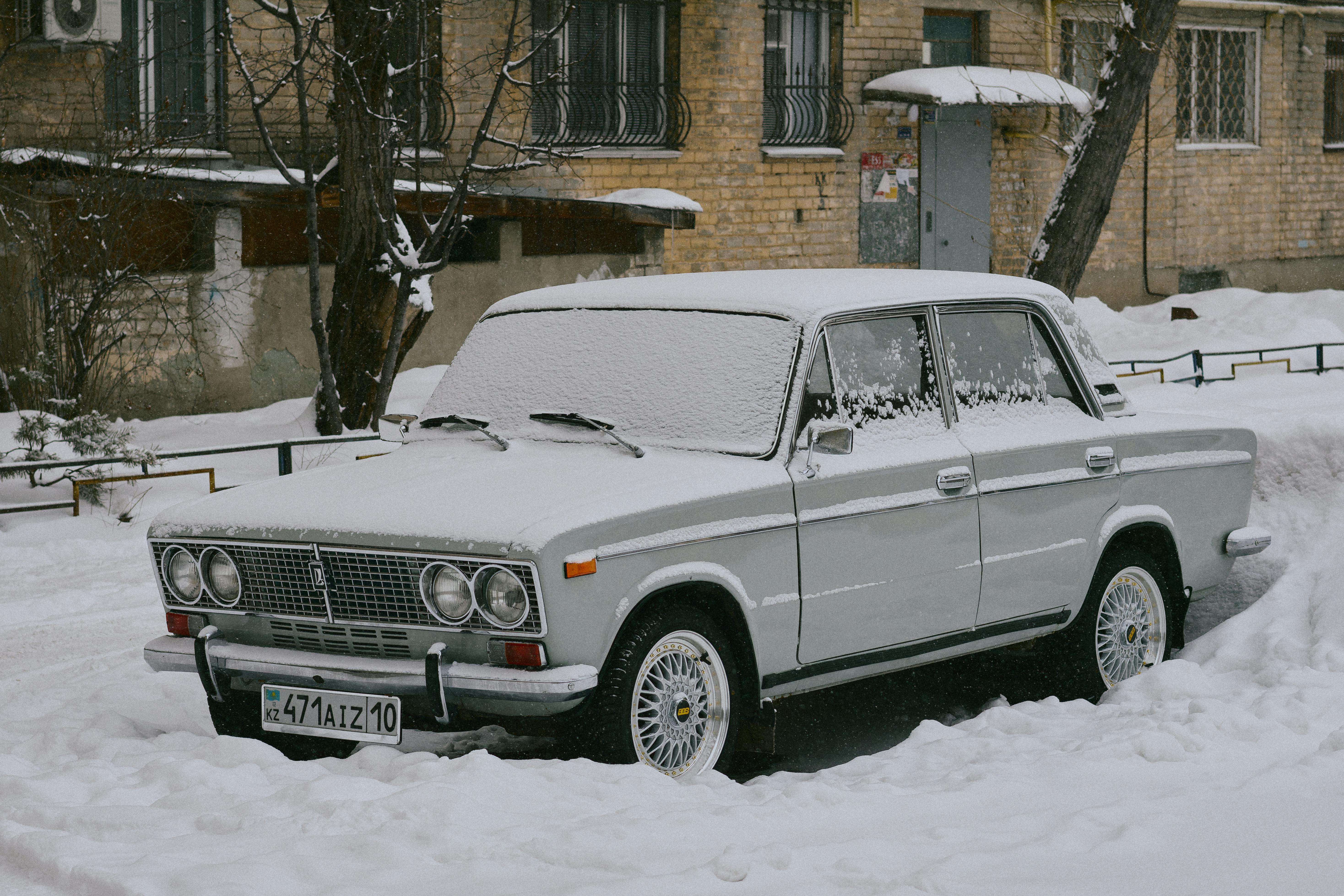 Kostenlos Ein mit Schnee bedeckter Oldtimer parkt vor einem Wohnhaus in der Stadt. Stock-Foto