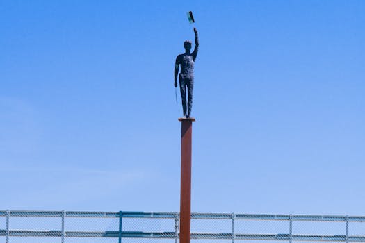 A striking statue of a figure with a flag stands prominently against a clear blue sky.