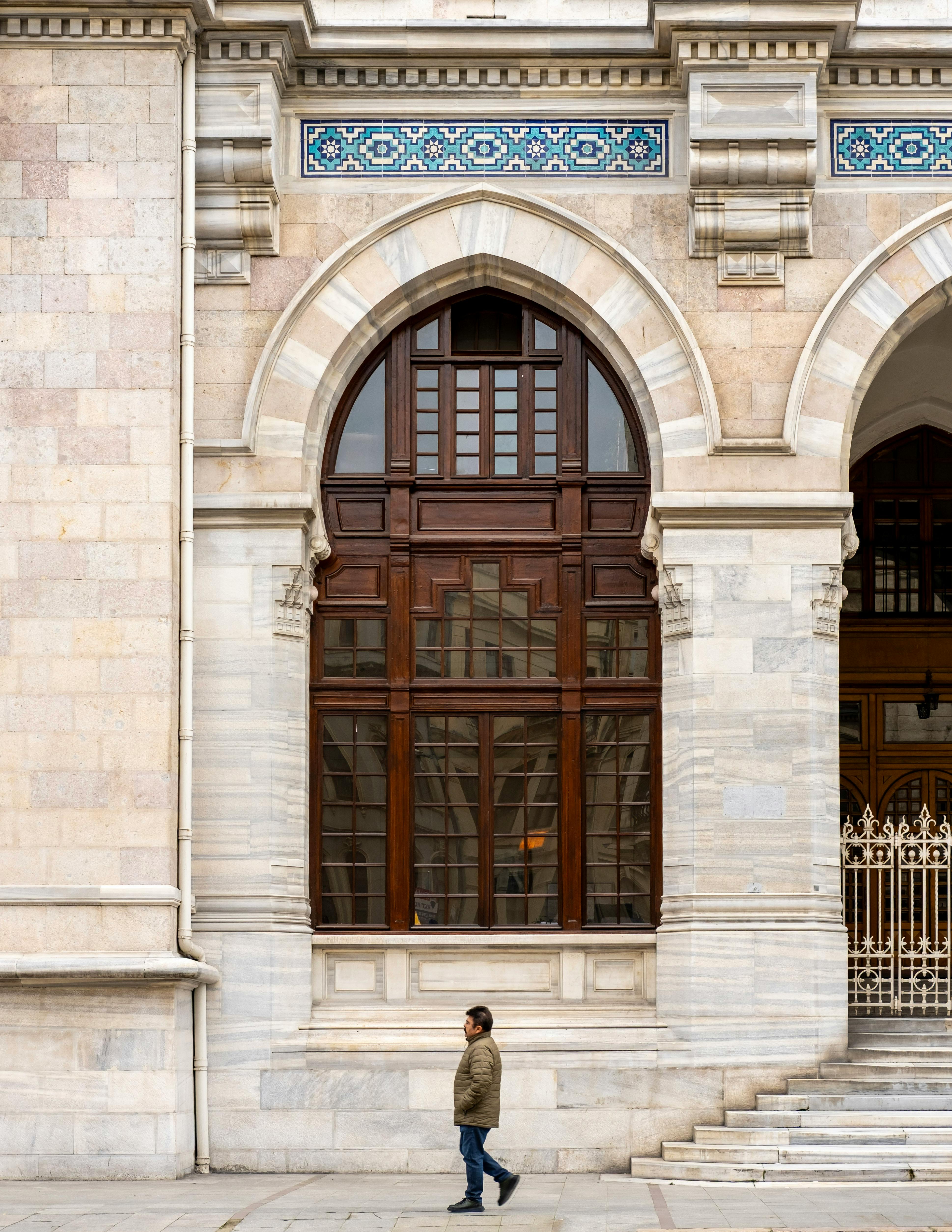 Δωρεάν Ένα άτομο περπατά δίπλα από μια ιστορική αρχιτεκτονική πρόσοψη με τοξωτά παράθυρα στην Κωνσταντινούπολη της Τουρκίας. Φωτογραφία από στοκ φωτογραφιών