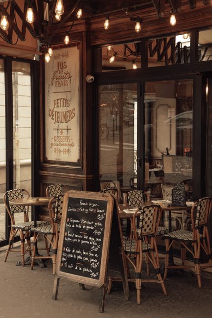 Cozy Parisian cafe with classic outdoor seating and a welcoming chalkboard menu.
