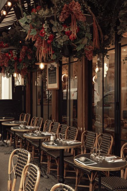 Experience the cozy atmosphere of a Parisian cafe terrace adorned with vibrant floral decor, ideal for outdoor dining.