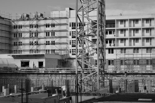 Free A monochromatic view of a building under construction with scaffolding and cranes. Stock Photo