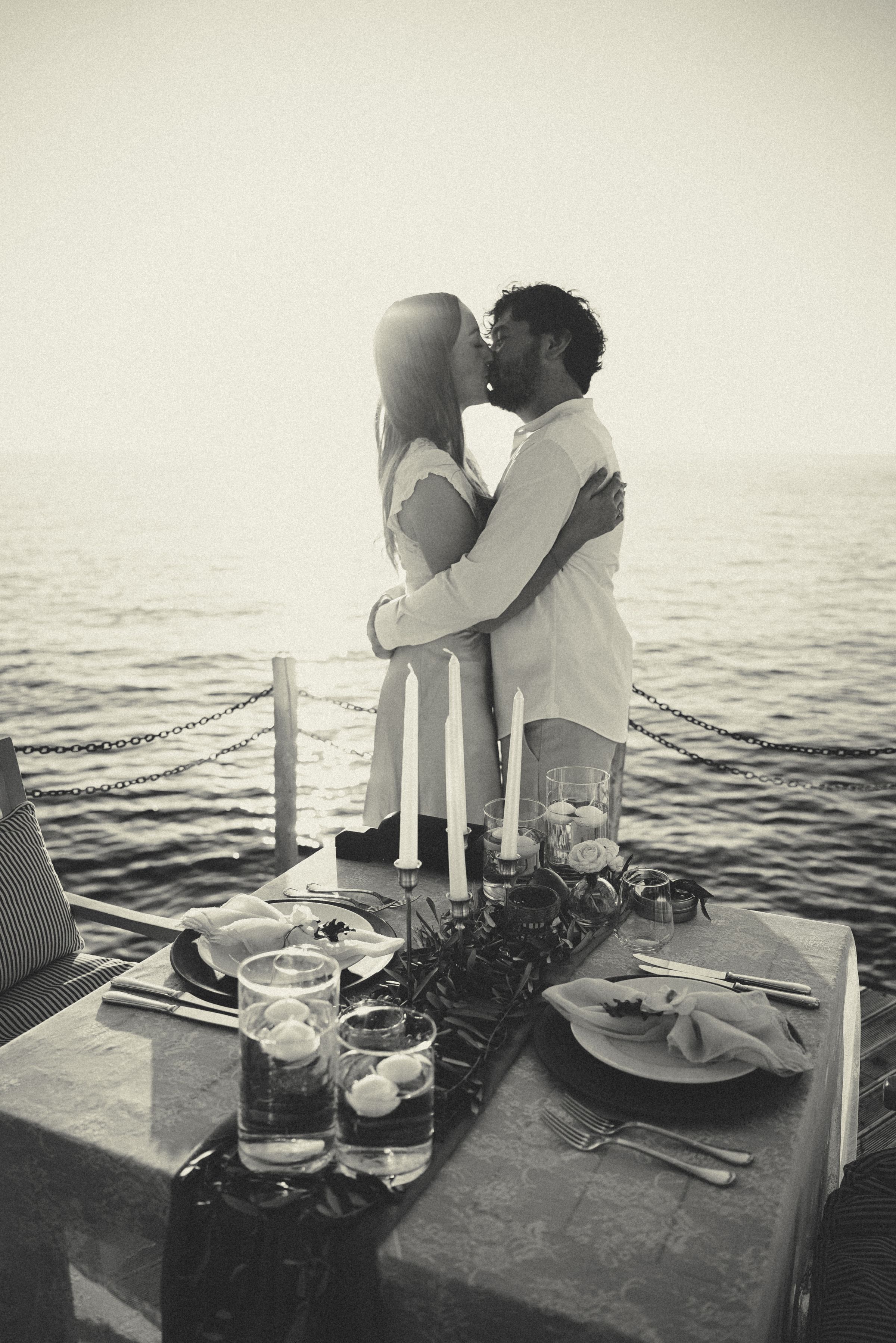 A candlelit dinner table by the sea at sunset