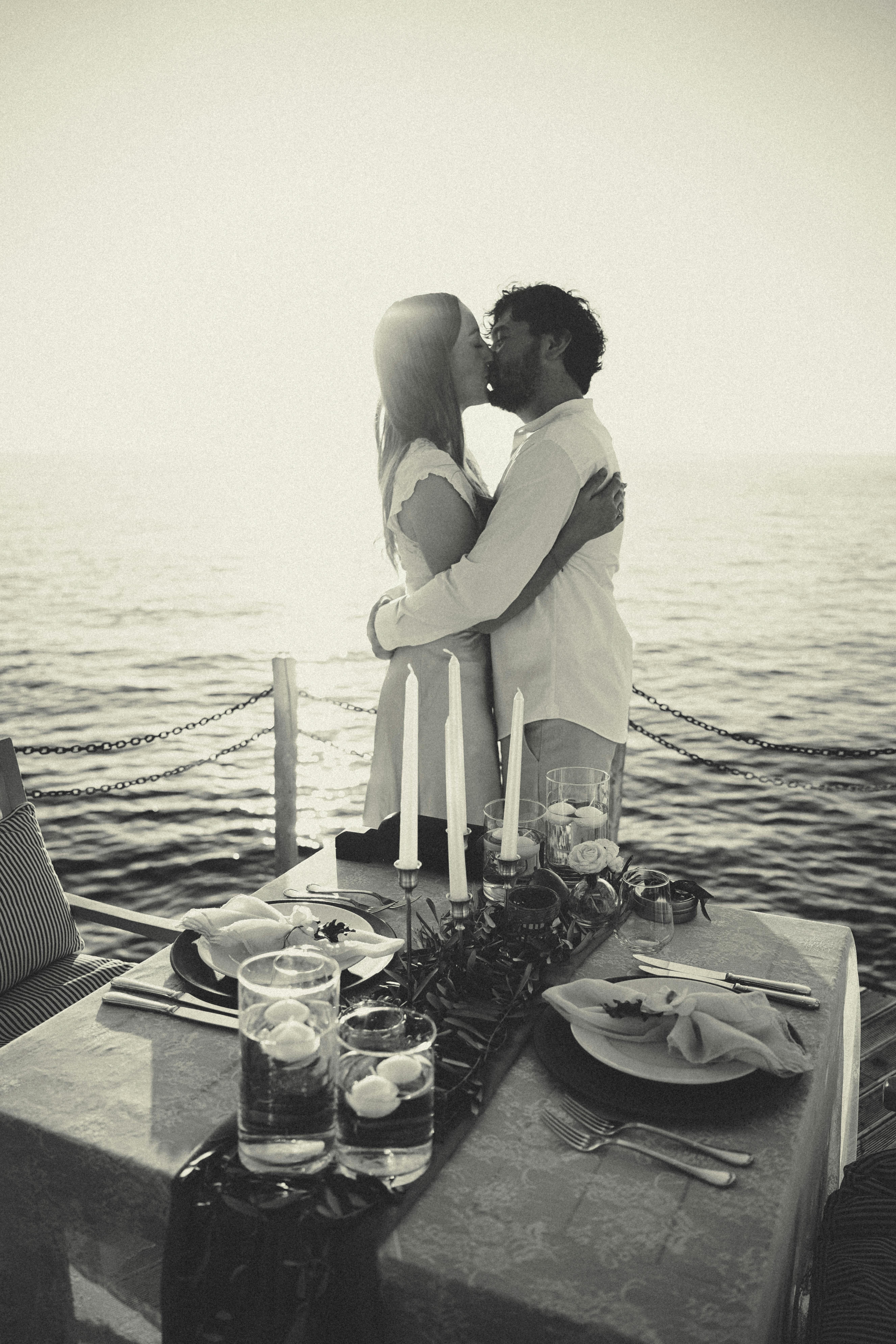 Kostenlos Ein Paar tauscht einen romantischen Kuss bei einem Abendessen im Kerzenschein am Meer im Sonnenuntergang aus. Stock-Foto