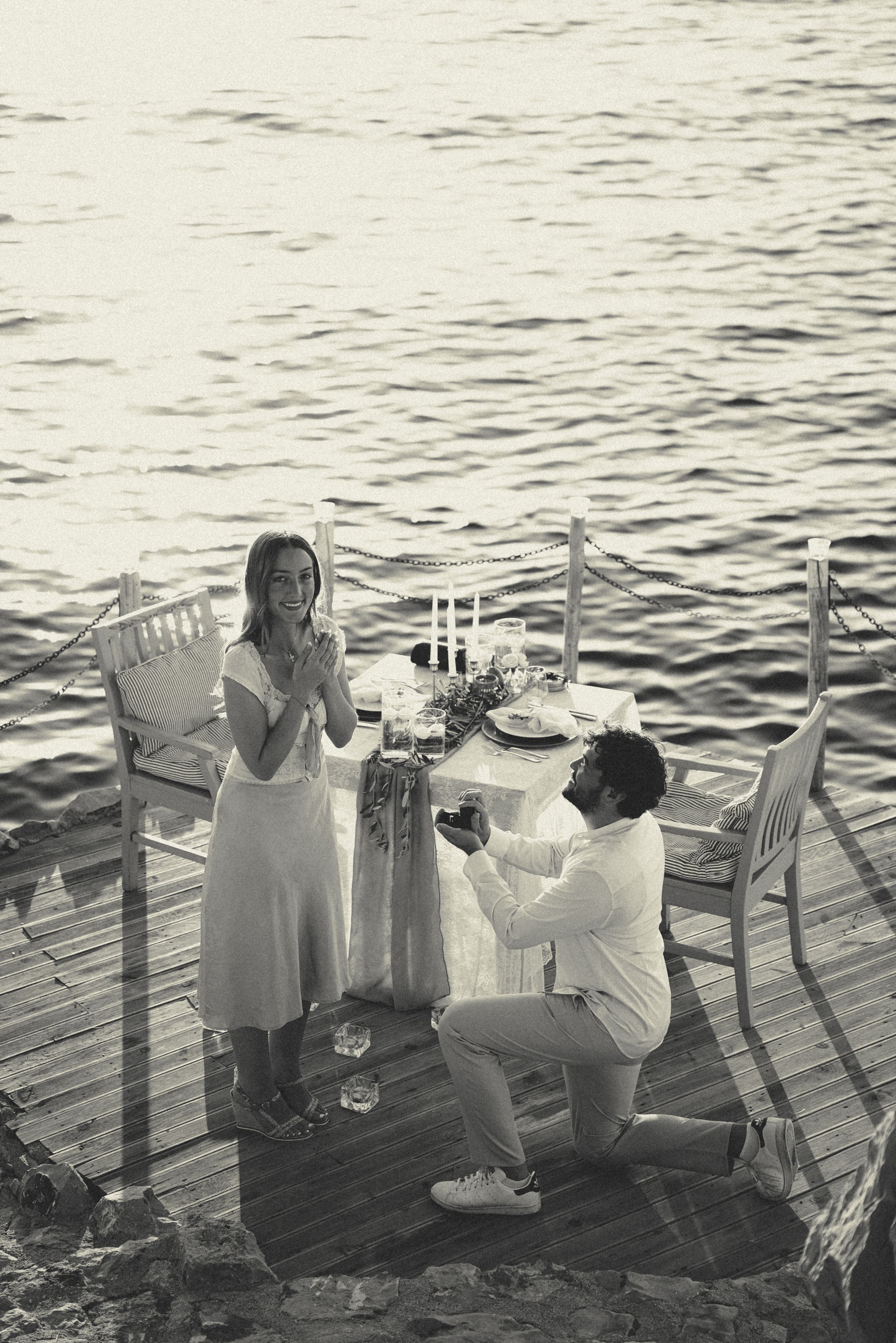 A couple by the sea at sunset, a quiet proposal unfolding