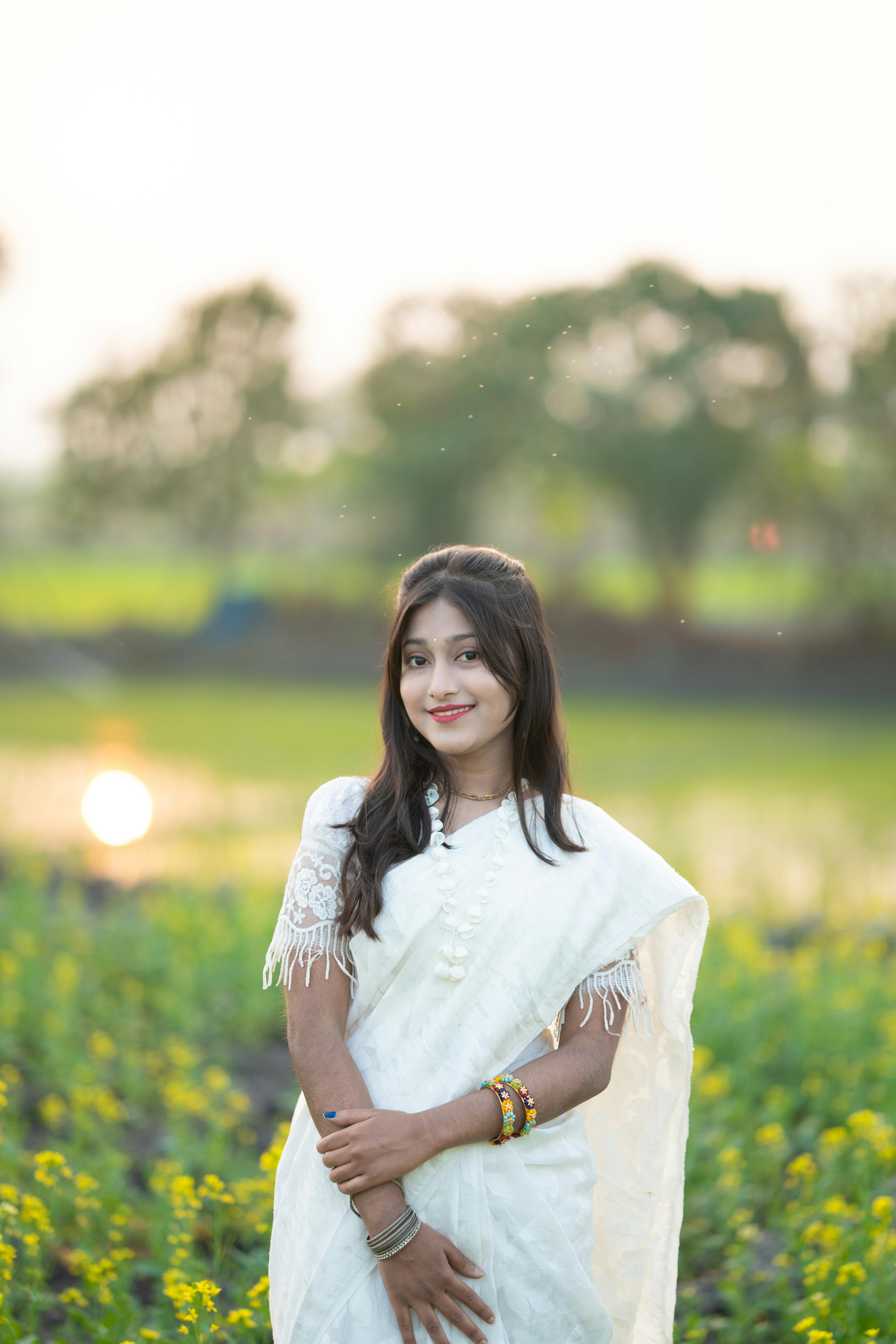 Kostenlos Junge Frau in weißer Tracht posiert in einem saftig grünen Feld bei sanftem, natürlichem Licht. Stock-Foto