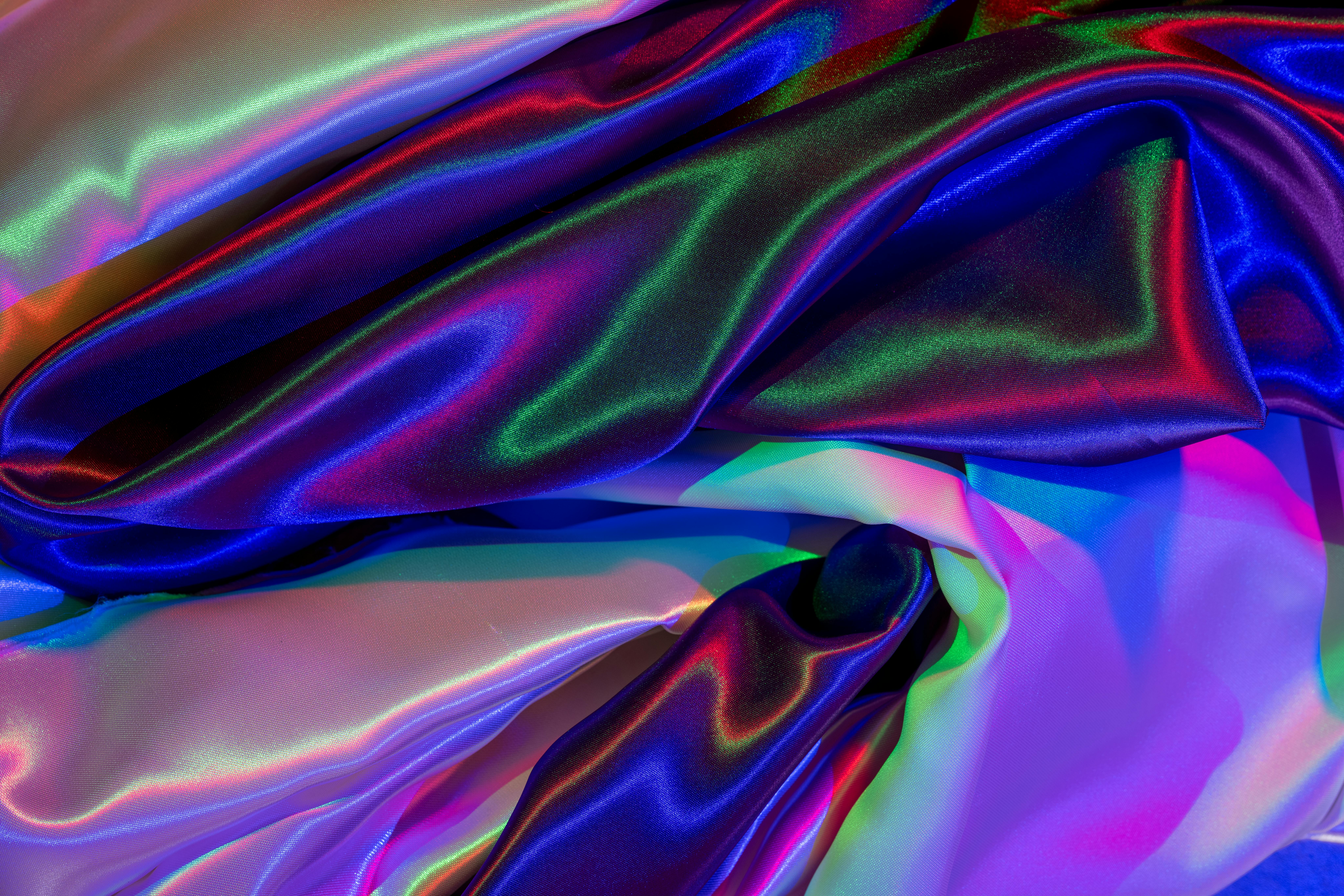 Free Colorful satin fabric displaying vibrant ripples and glossy textures under creative lighting. Stock Photo