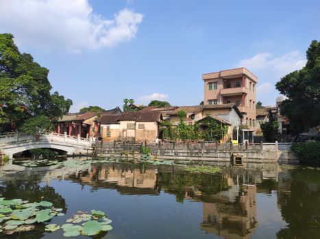 Charming view of traditional Chinese architecture by a tranquil pond in Dongguan, China.