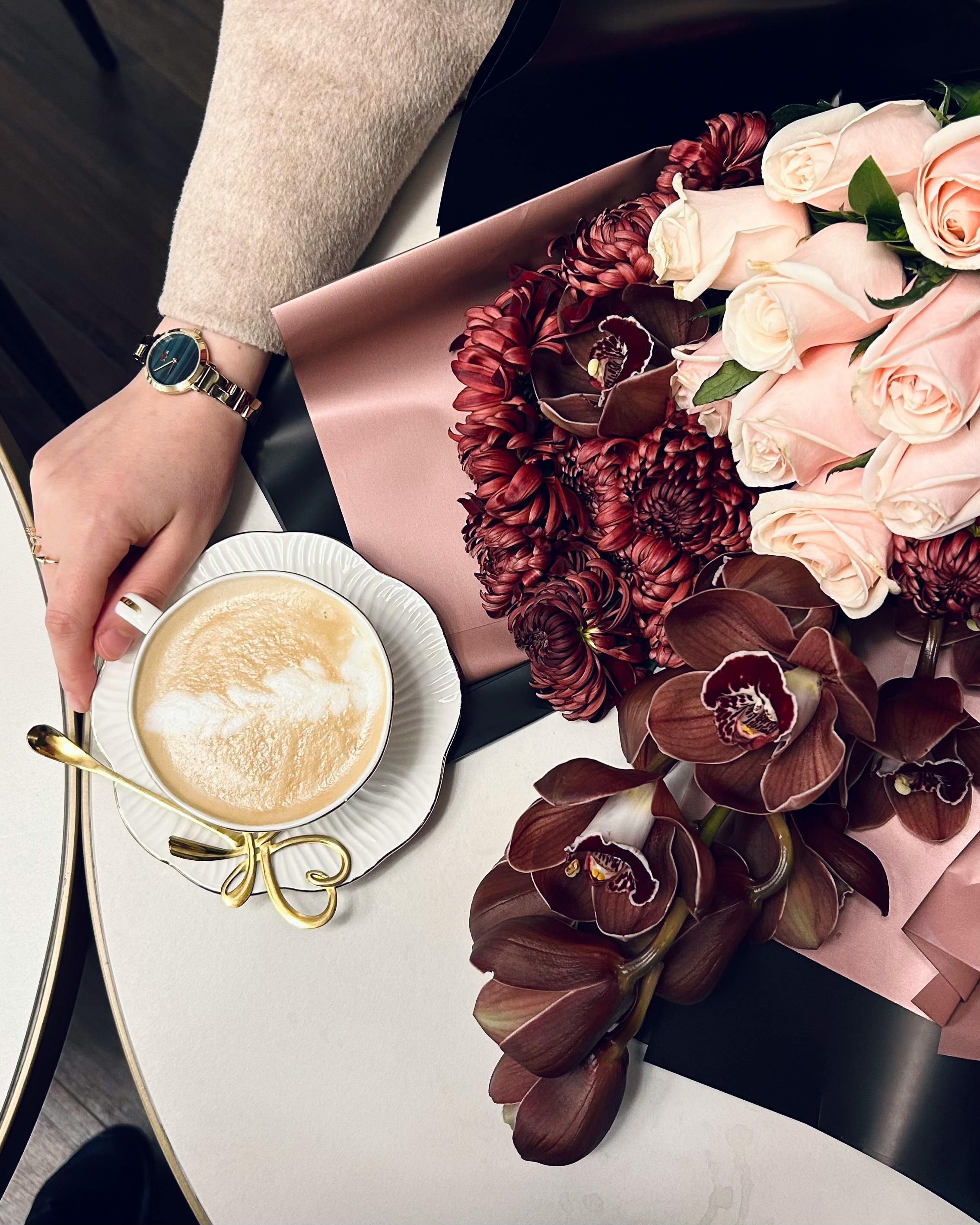 Kostenlos Draufsicht auf einen Latte Macchiato mit einem rosa-burgunderfarbenen Blumenstrauß in gemütlicher Innenatmosphäre. Stock-Foto