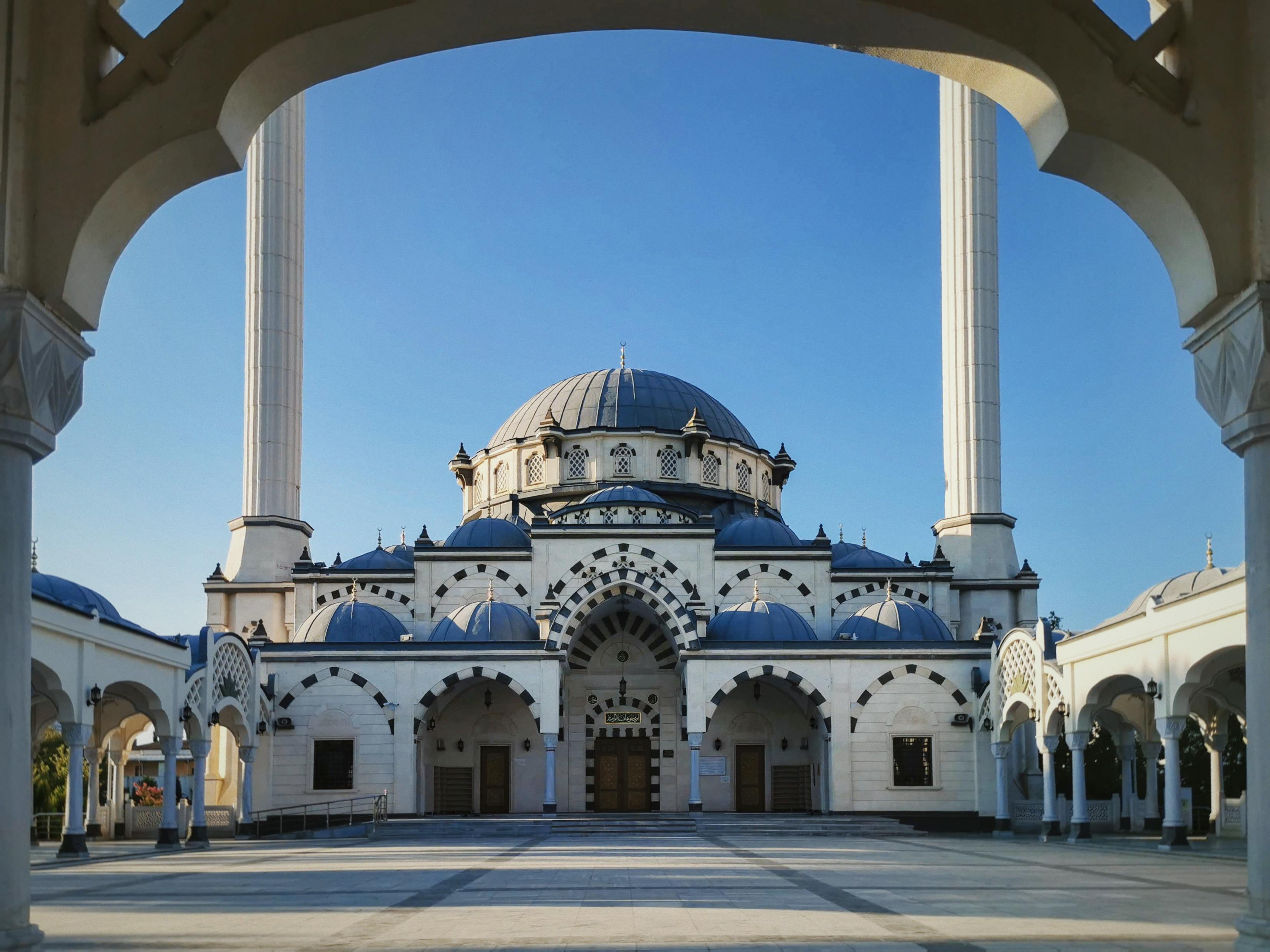 Kostenlos Wunderschöne Architekturaufnahme einer Moschee vor blauem Himmel, aufgenommen bei Tageslicht. Stock-Foto