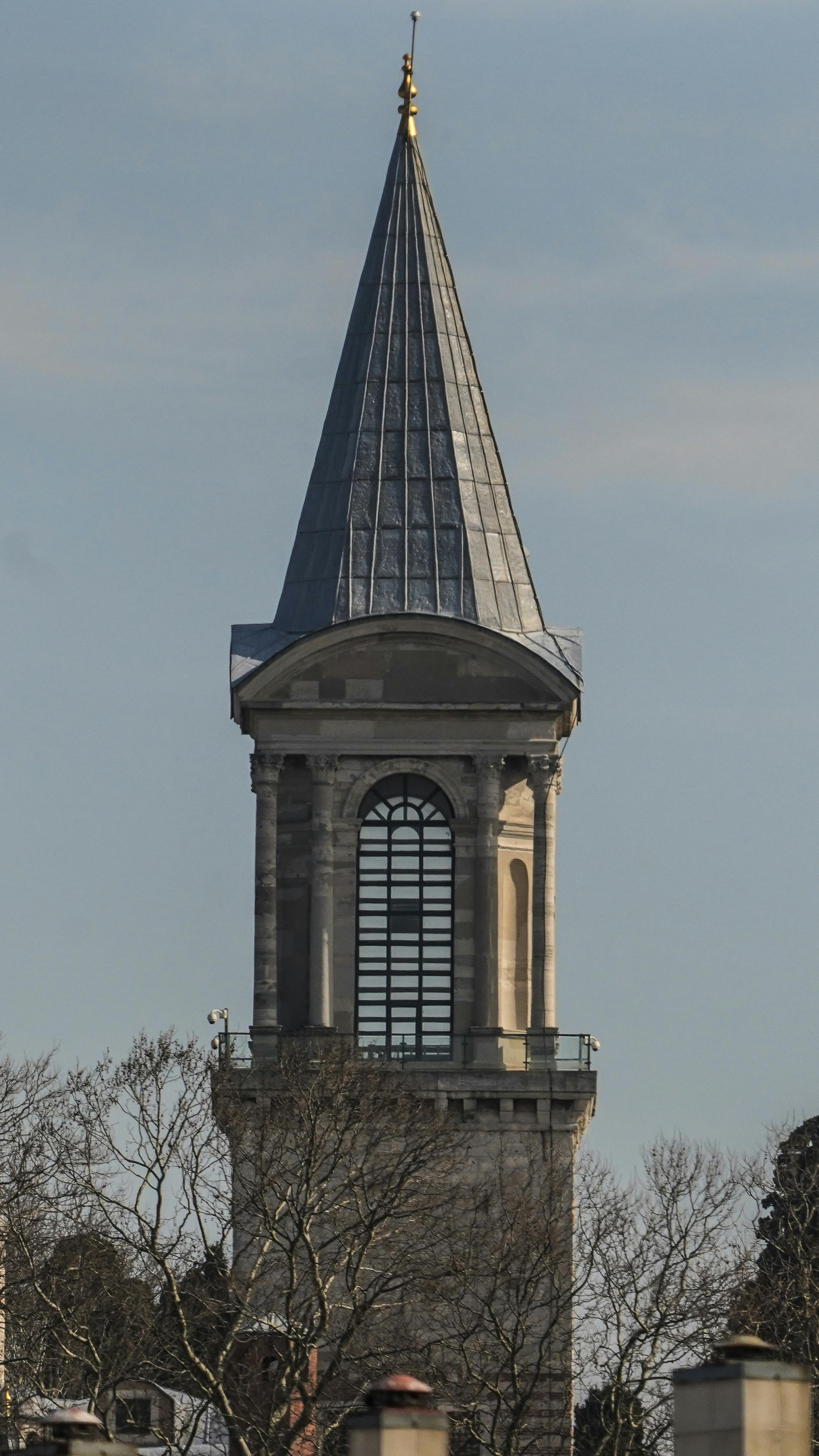 Δωρεάν Ένας ψηλός, ιστορικός πύργος με οθωμανικά αρχιτεκτονικά στοιχεία στέκει κάτω από έναν καθαρό ουρανό, περιτριγυρισμένος από γυμνά δέντρα. Φωτογραφία από στοκ φωτογραφιών