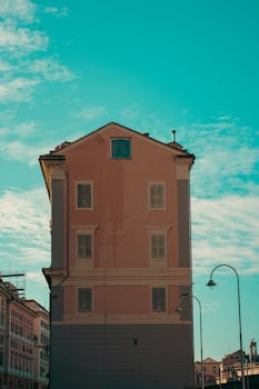 A tall historic building against a clear blue sky in Genoa, Italy, showcasing classic architecture.