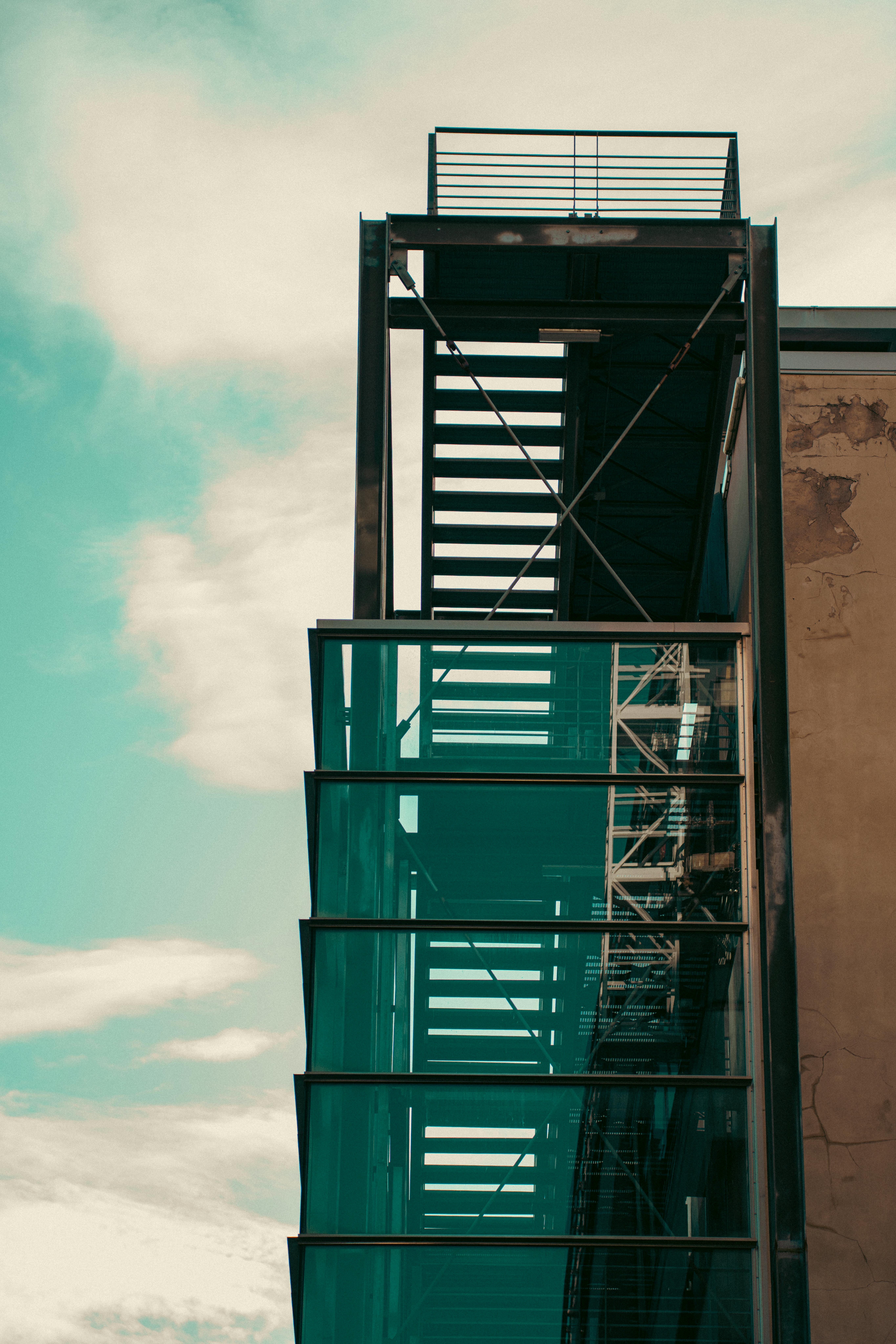 Free Vertical glass and metal staircase against a cloudy sky in Genoa, Italy. Stock Photo