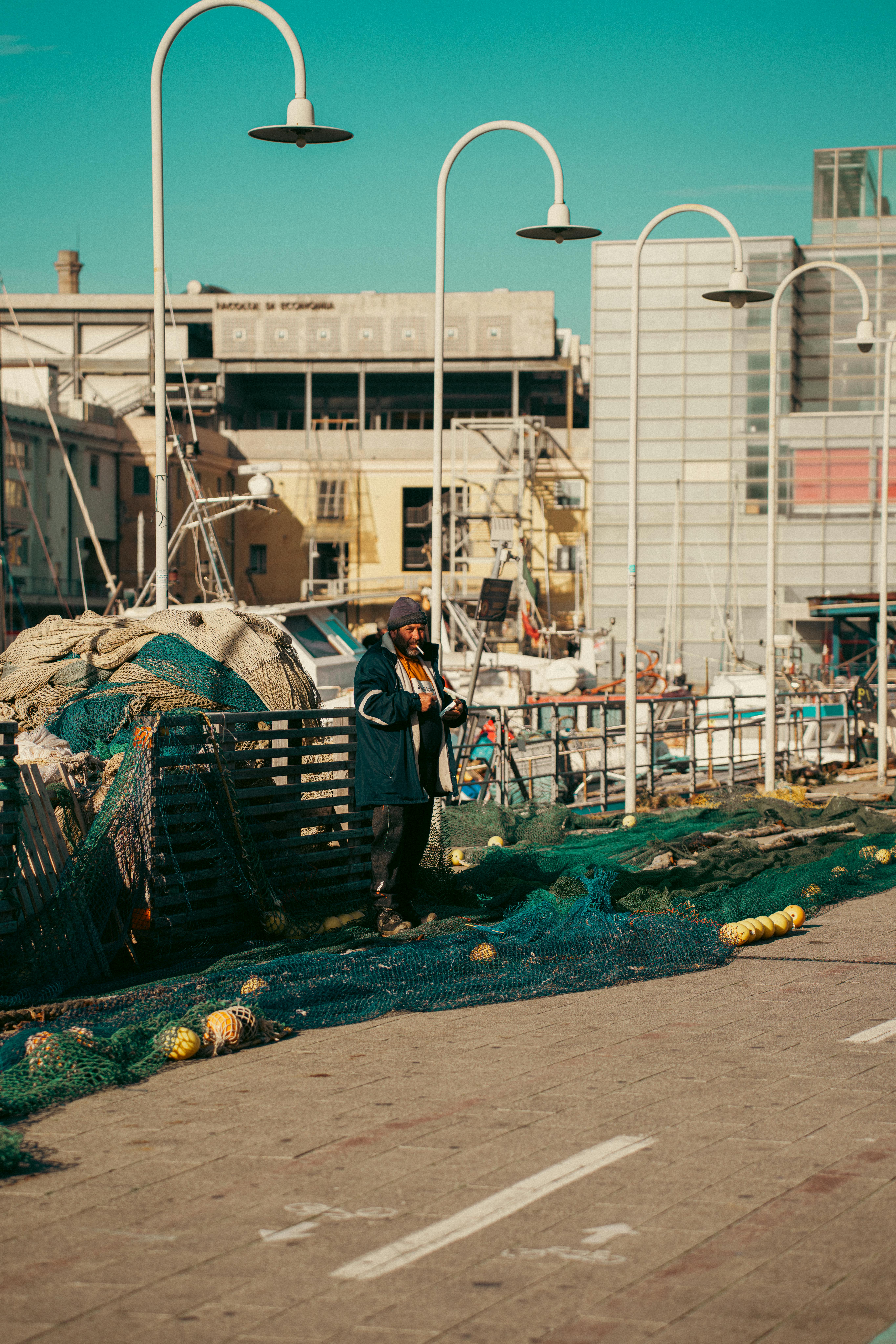 Δωρεάν Ψαράς στέκεται δίπλα σε δίχτυα ψαρέματος στο λιμάνι της Γένοβας, απαθανατίζοντας την καθημερινή ζωή στο λιμάνι. Φωτογραφία από στοκ φωτογραφιών