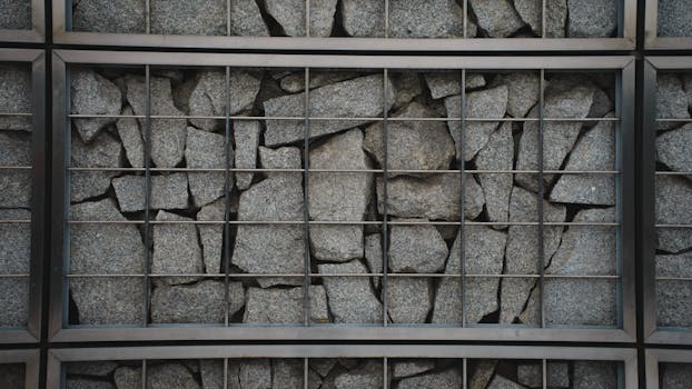 An iron grid encases a rugged rock wall, showcasing industrial architecture in Warsaw, Poland.