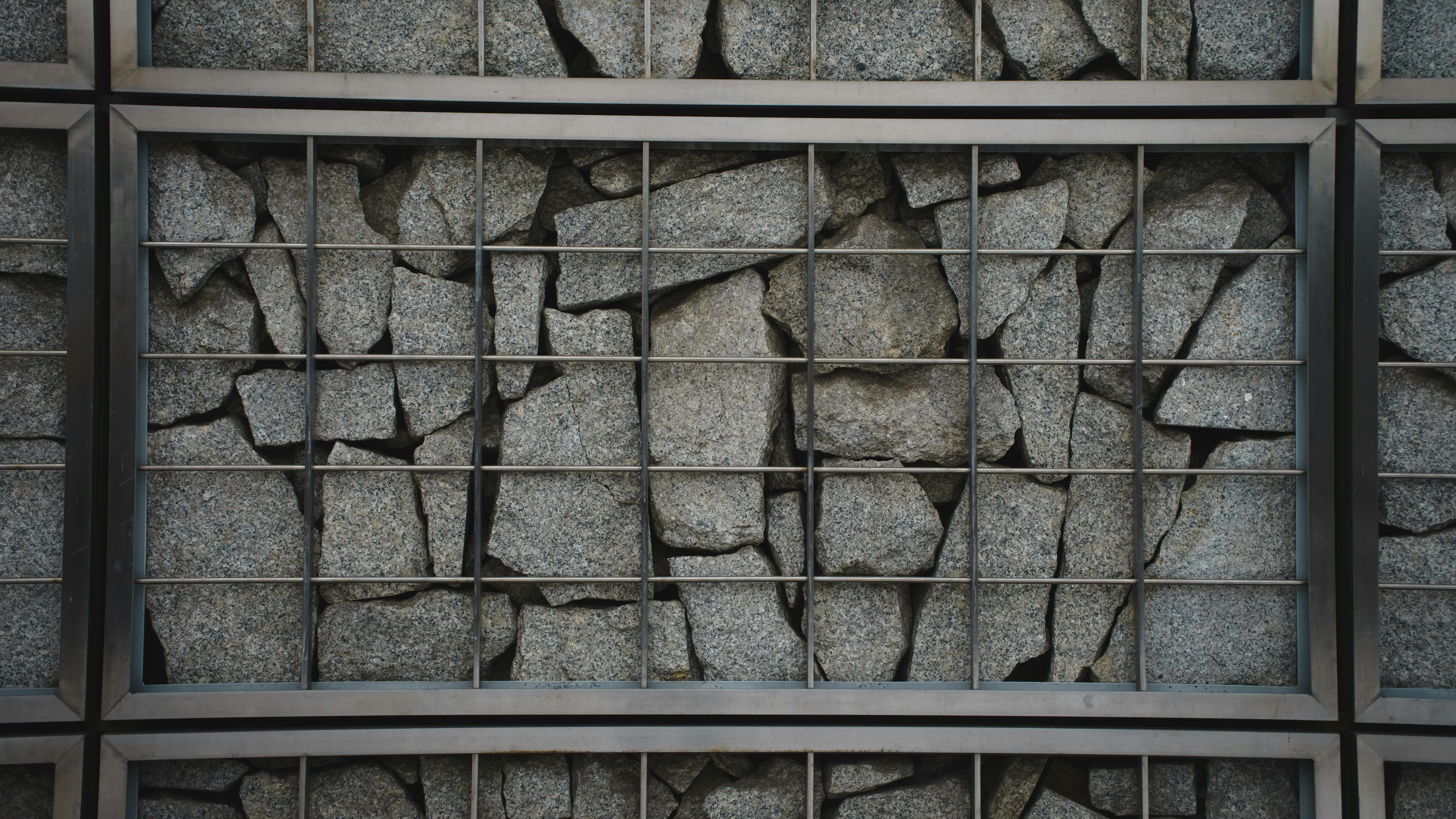 Free An iron grid encases a rugged rock wall, showcasing industrial architecture in Warsaw, Poland. Stock Photo