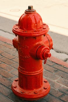 Bright red fire hydrant on a brick sidewalk in an urban setting, ideal for street scene imagery.
