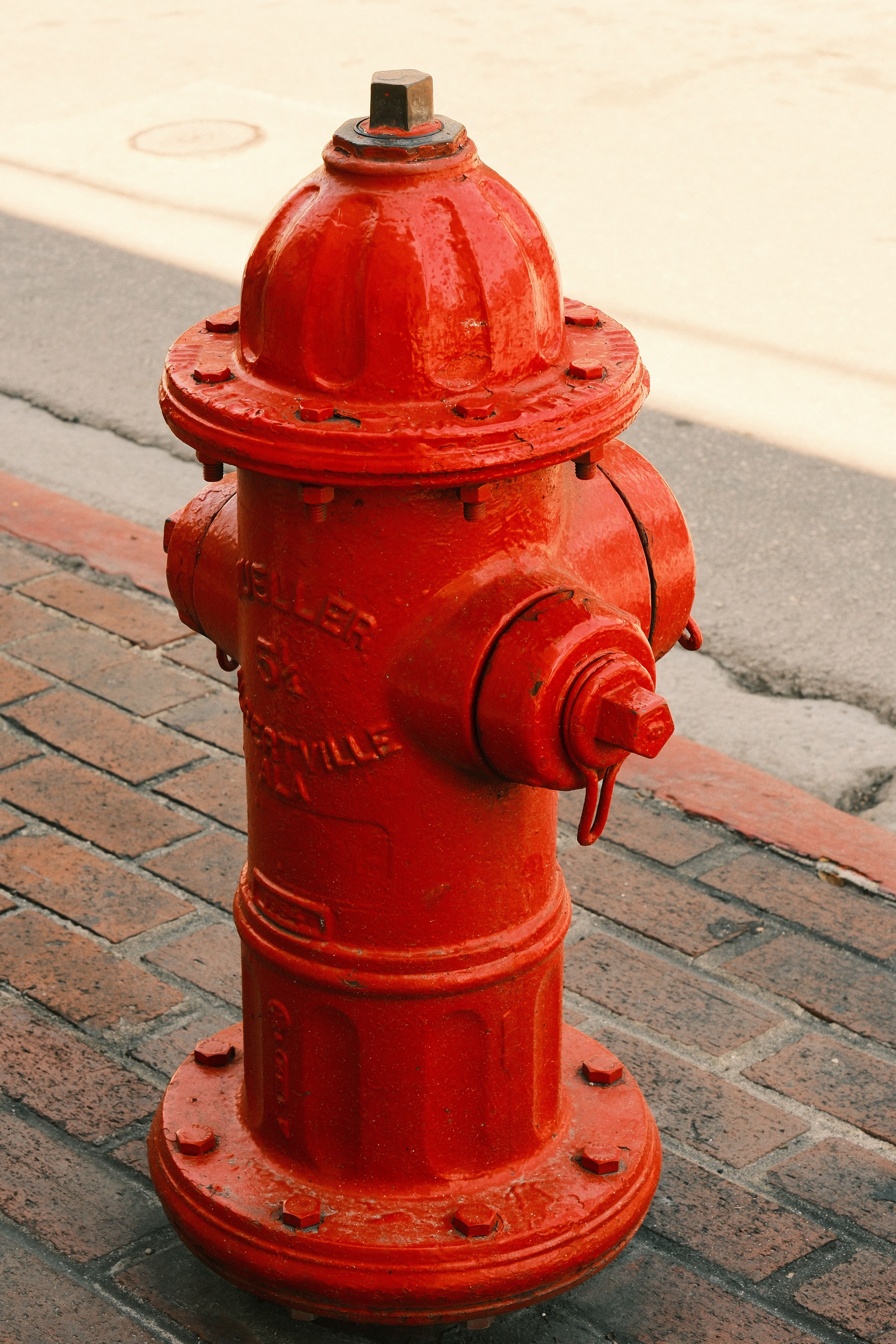 grátis Hidrante vermelho brilhante em uma calçada de tijolos em um ambiente urbano, ideal para imagens de cenas de rua. Foto profissional