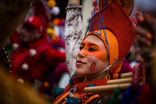 Colorful portrait of a festival performer in traditional orange costume and makeup.