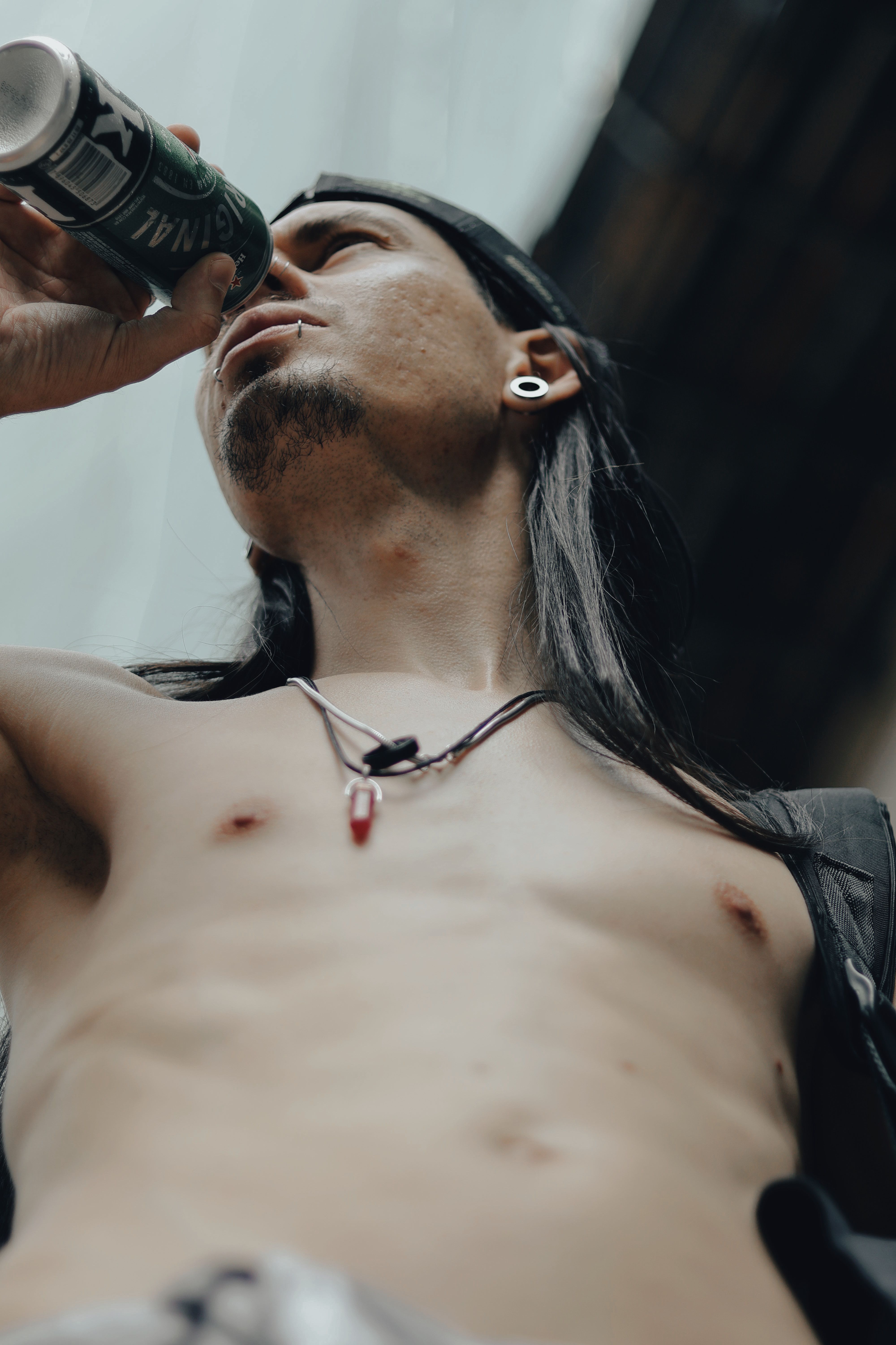Shirtless young man drinking a cold beverage outdoors in São Paulo, Brazil. Urban vibes.